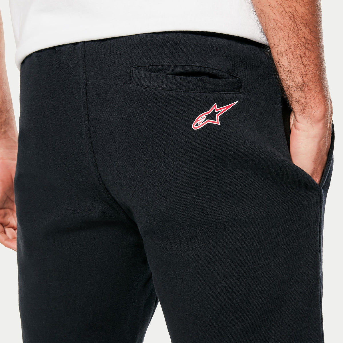 Alpinestars Dunker Short, czarne polarowe spodenki treningowe, zbliżenie na tylną kieszeń z czerwono-białym logo Ageless, miękka tekstura materiału, sportowy design