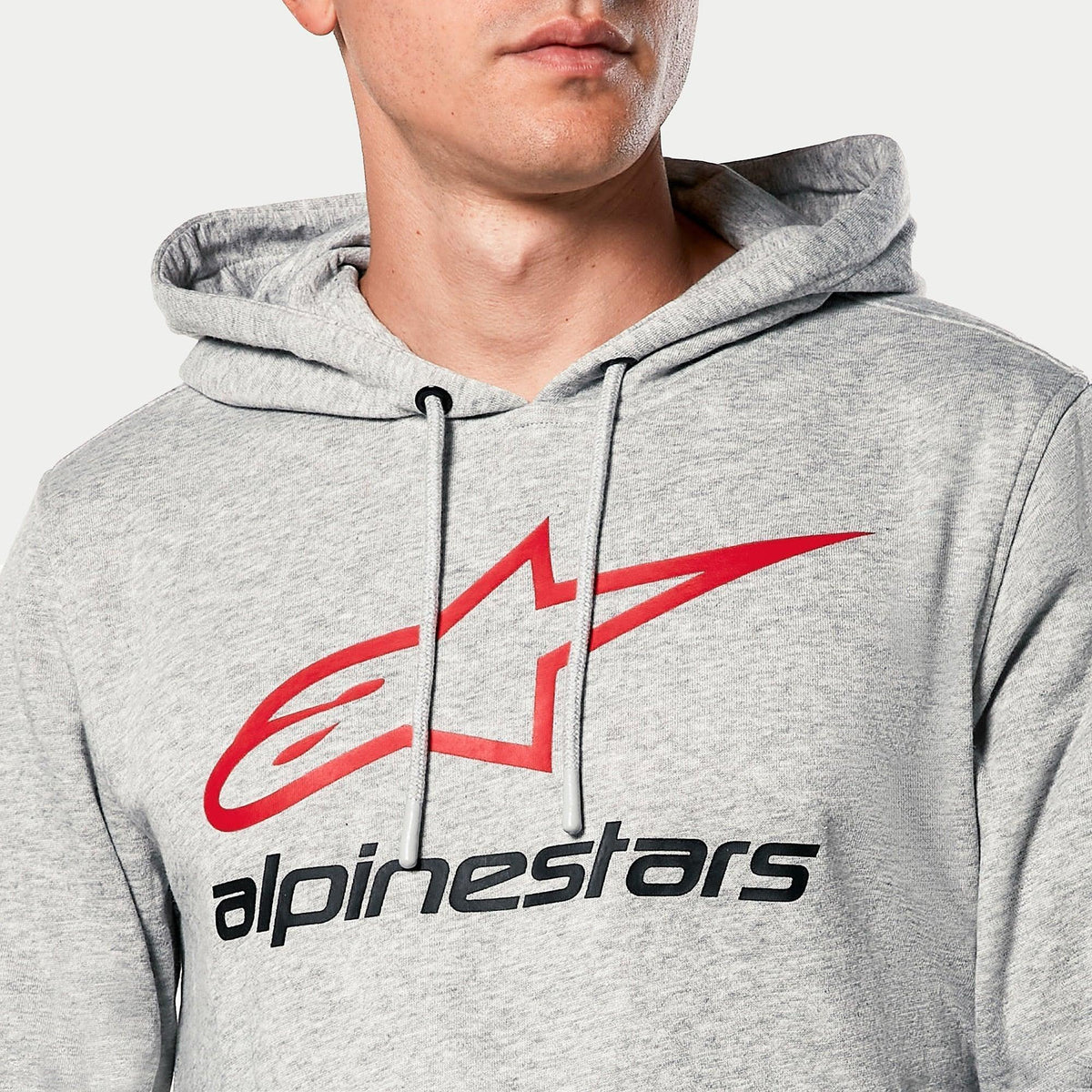 Bluza z kapturem Alpinestars Always V3, Grey Heather, zbliżenie na klatkę piersiową z czerwonym logo gwiazdy i czarnym napisem Alpinestars, kaptur z dżersejową podszewką i szarymi sznurkami, codzienna odzież streetwearowa w stylu motorsport