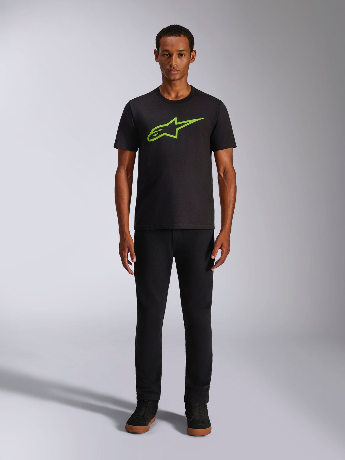 Alpinestars Ageless 2.0 CSF Tee, Short Sleeve T-Shirt, Black with Bright Green Logo, worn by model with black pants, casual motorsport-inspired design