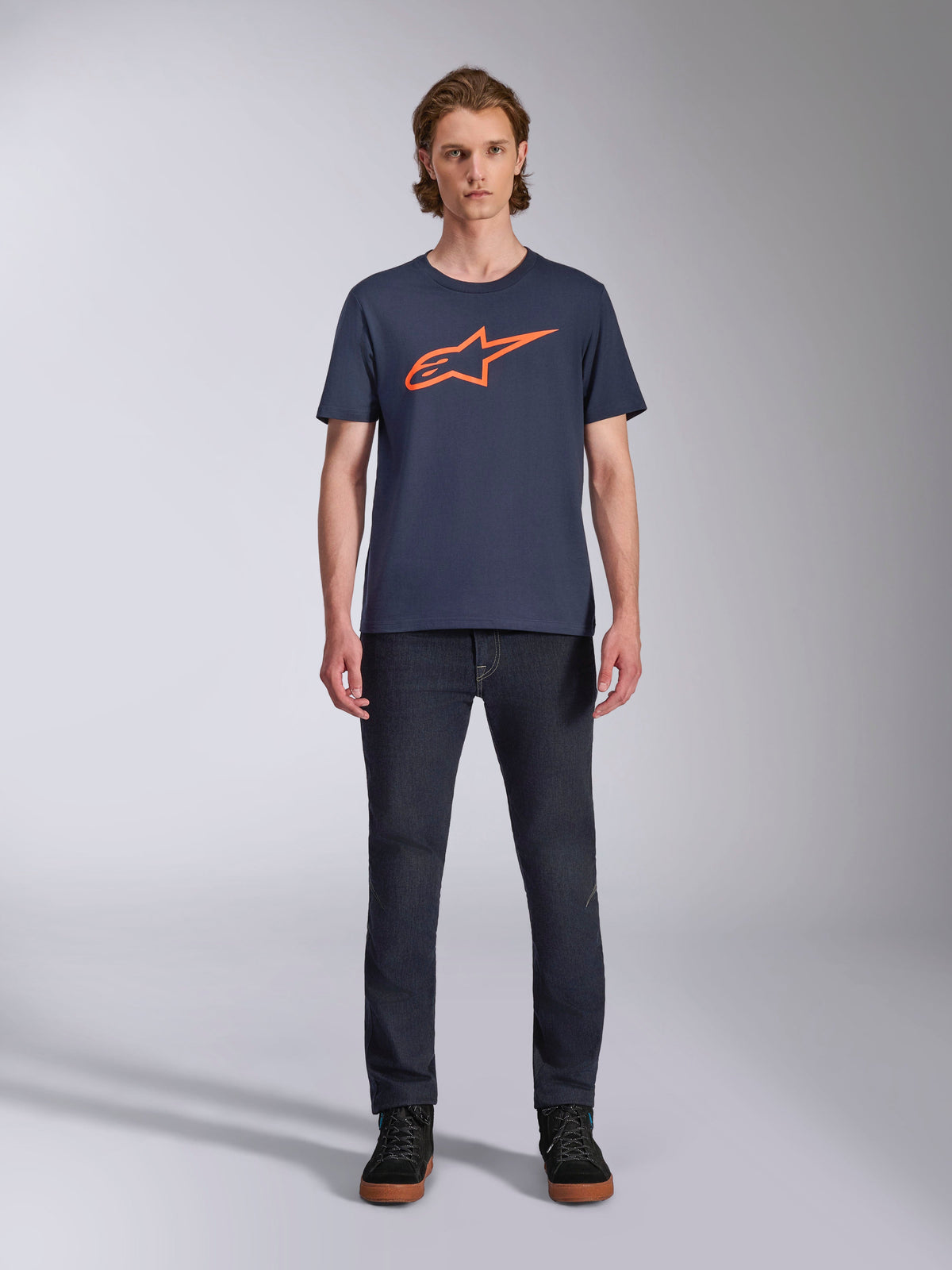 Alpinestars Ageless 2.0 CSF Tee, Short Sleeve T-Shirt, Navy Blue with Orange Alpinestars Logo, worn by model with dark jeans and sneakers, Casual Motorsport Streetwear
