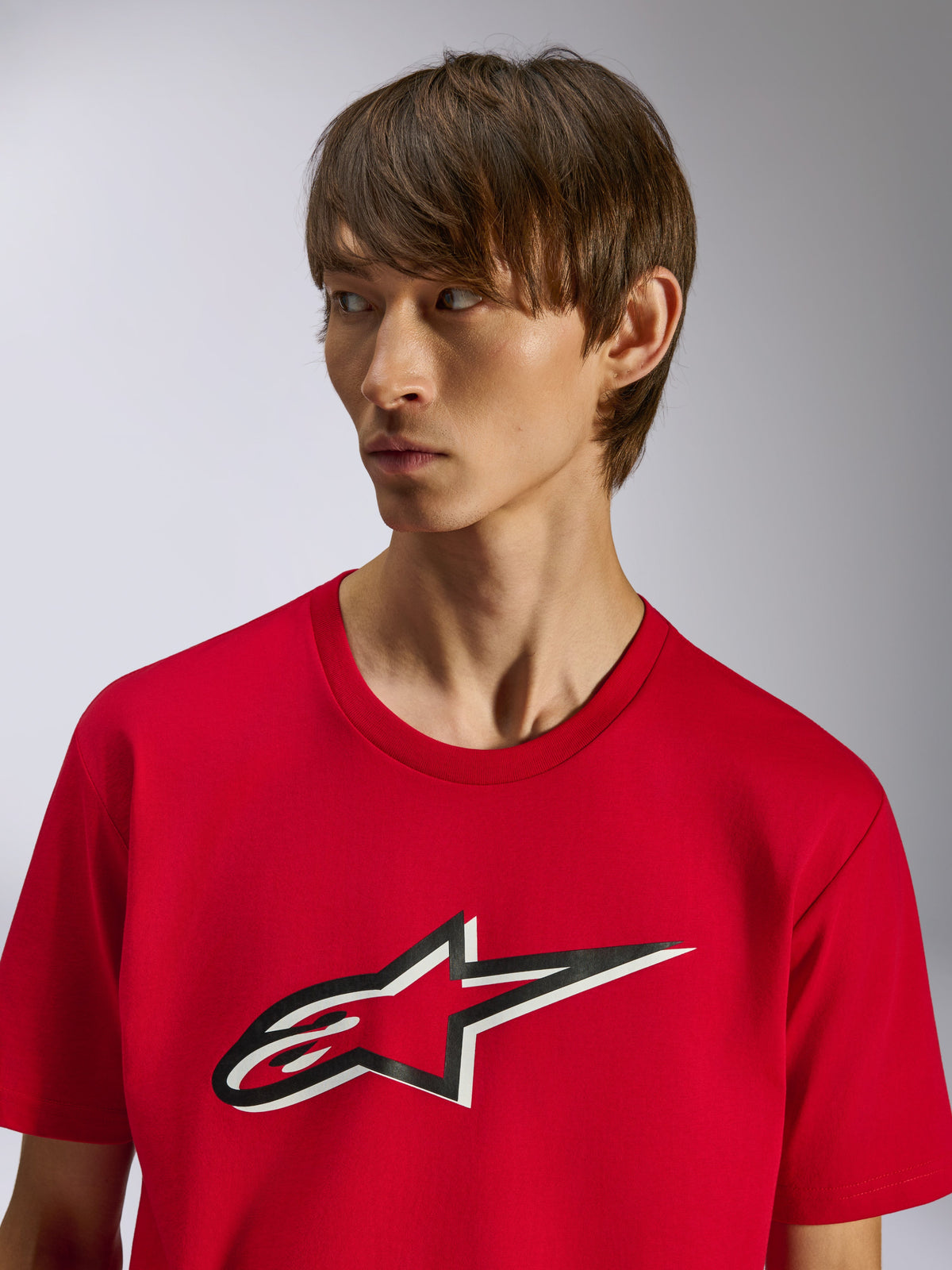 Alpinestars Ageless Shadow CSF Tee, koszulka z krótkim rękawem, czerwona, z przodu logo gwiazdy Ageless z efektem czarno-białego cienia, noszona przez modela, codzienny design inspirowany sportami motorowymi