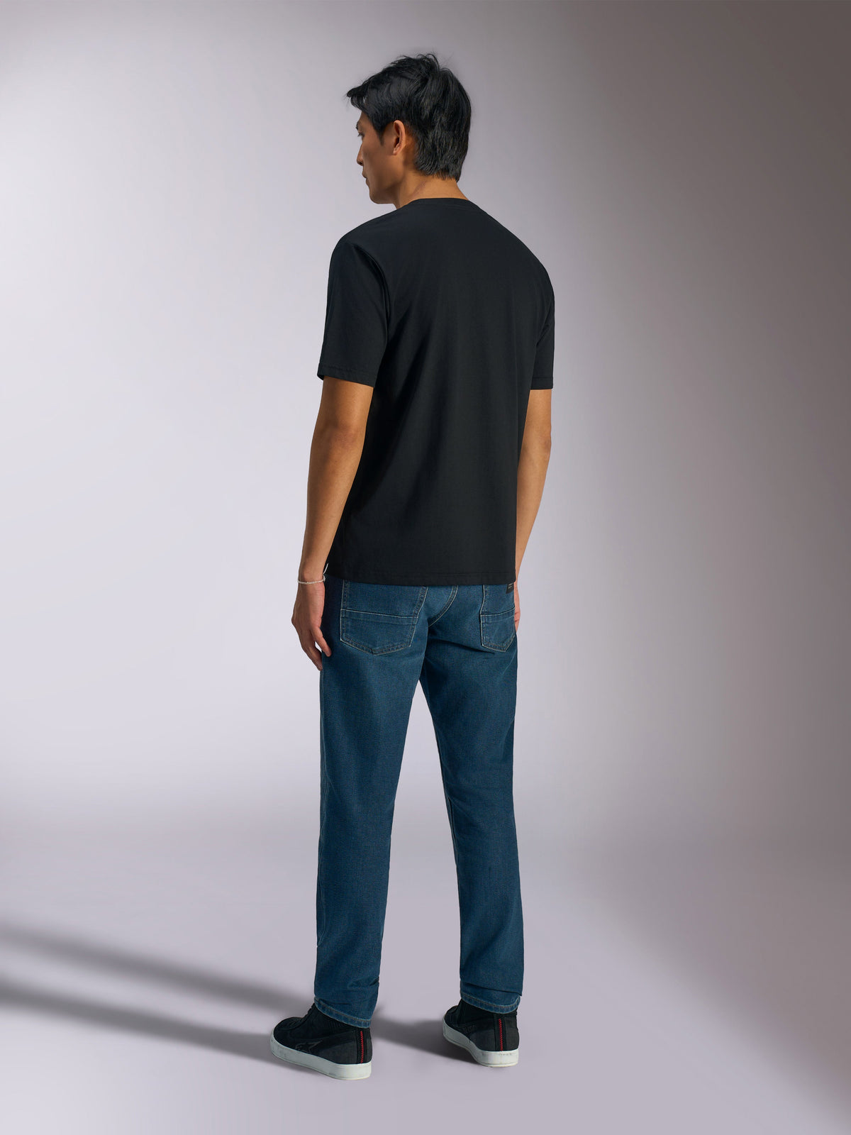 Alpinestars Ageless Shadow CSF Tee, Short Sleeve T-Shirt, Black, Back View, worn with blue jeans and black sneakers, casual motorsport-inspired streetwear