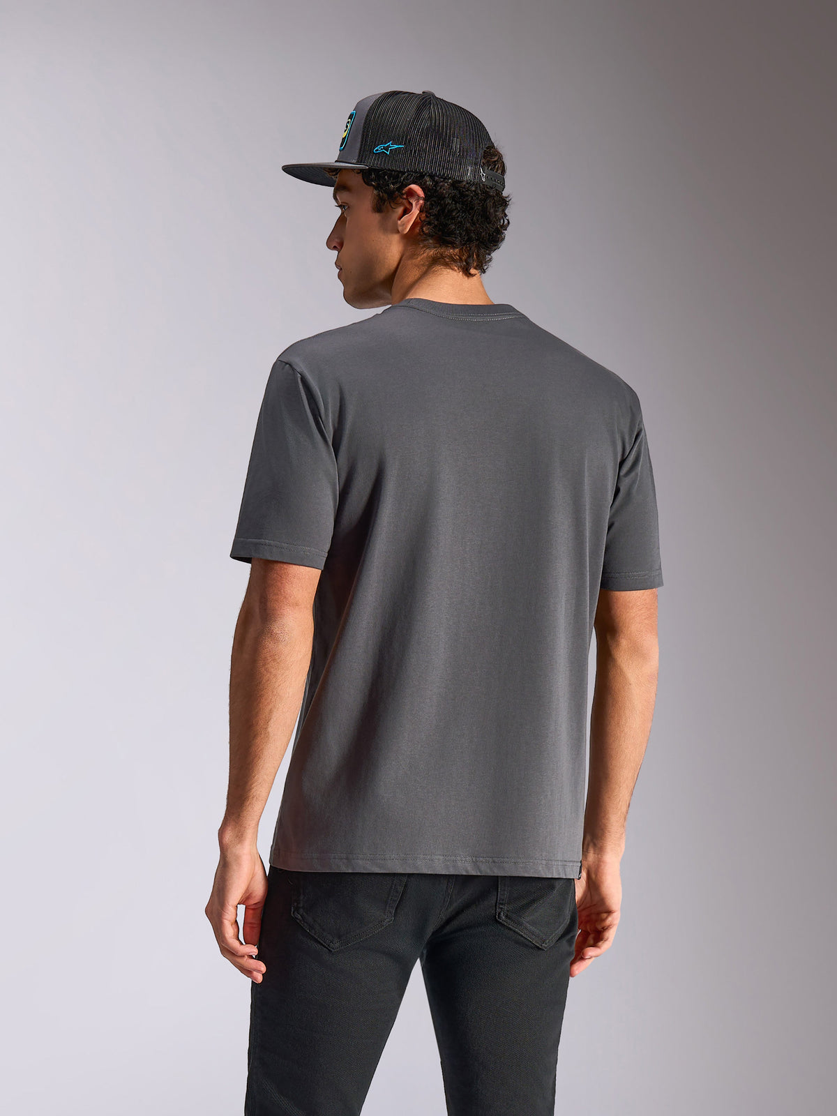 Alpinestars Blaze 2.0 CSF Tee, Short Sleeve T-Shirt, Charcoal Gray, back view, worn with black jeans and a mesh cap, casual motorsport-inspired streetwear