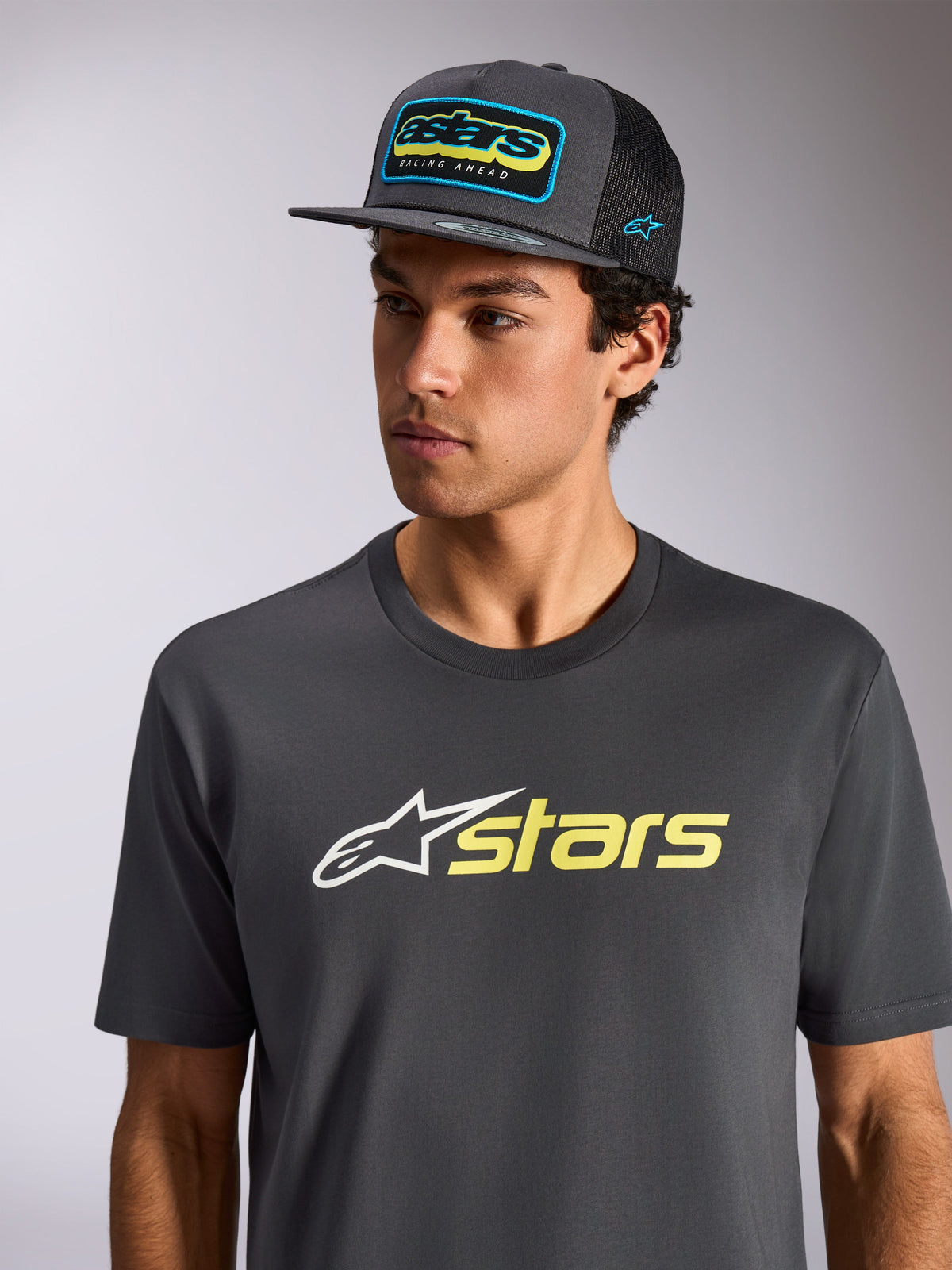 Alpinestars Blaze 2.0 CSF Tee, Short Sleeve T-Shirt, Charcoal with White and Hi-Vis Yellow Logo, worn with a matching charcoal mesh-back cap, casual motorsport-inspired sportswear