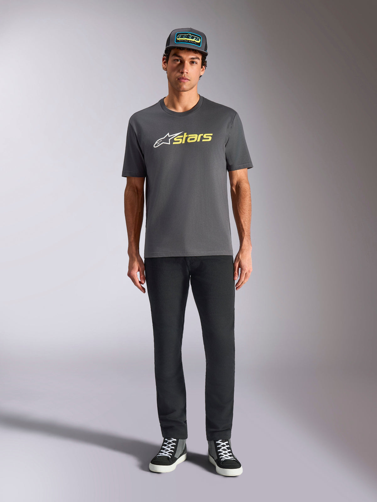 Alpinestars Blaze 2.0 CSF Tee, Short Sleeve T-Shirt, Charcoal Gray with White and Hi-Vis Yellow logo, worn with black pants and a matching trucker hat, casual motorsport lifestyle