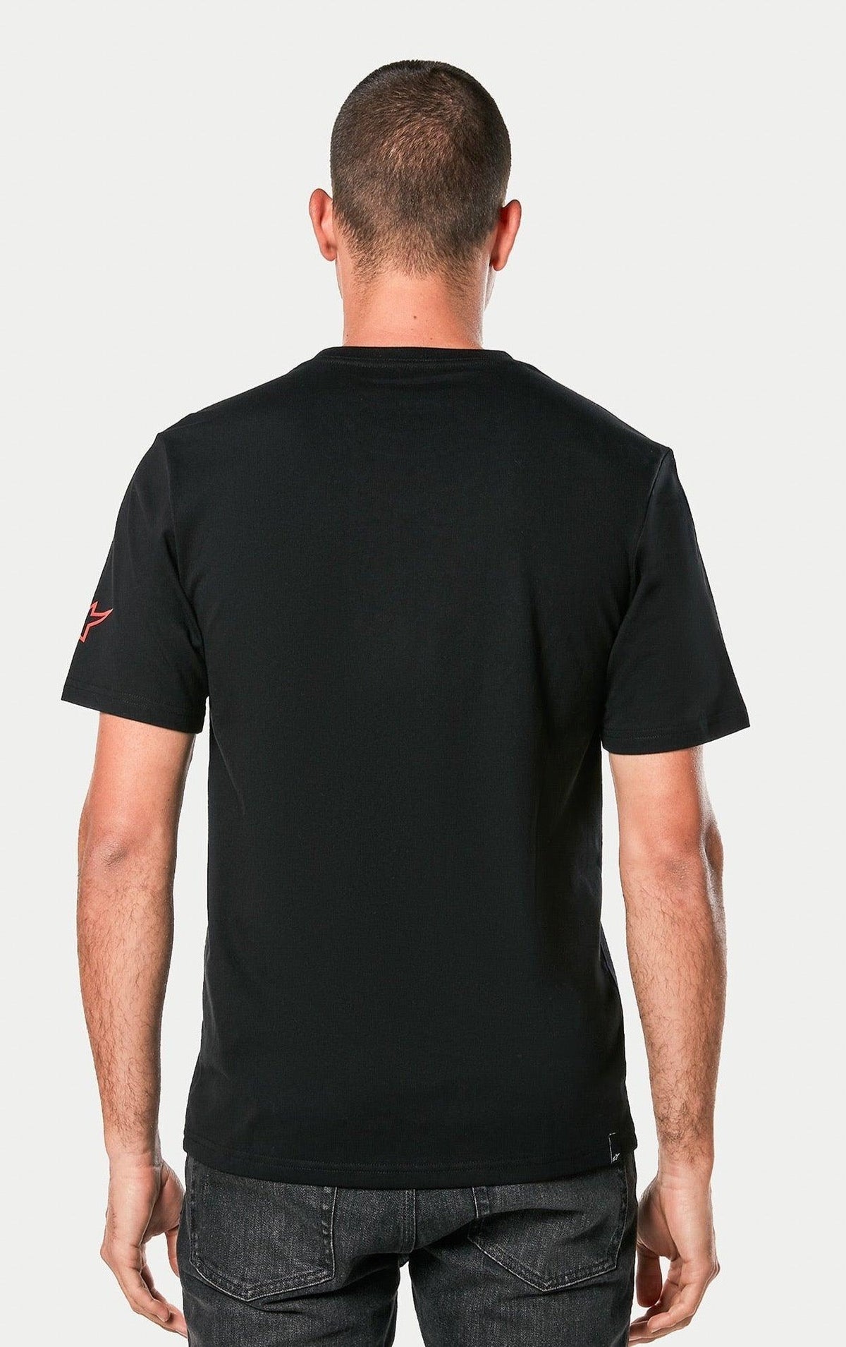 Alpinestars Linear Wordmark 2.0 CSF Tee, czarna, widok z tyłu na osobę noszącą koszulkę z krótkim rękawem, z czerwonym logo Ageless na rękawie, casualowa odzież streetwearowa w stylu motorsportowym.