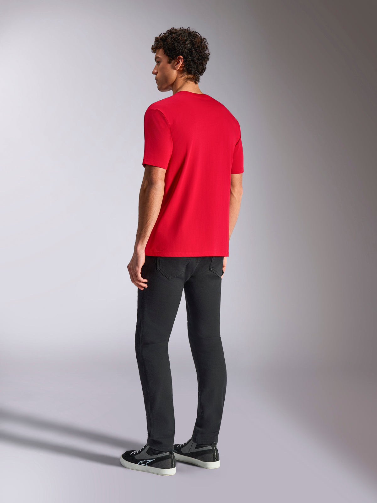 Alpinestars Ride 4.0 CSF Tee, czerwona koszulka z krótkim rękawem, widok z tyłu na modelu w czarnych spodniach i trampkach, casualowy streetwear w stylu motorsportowym