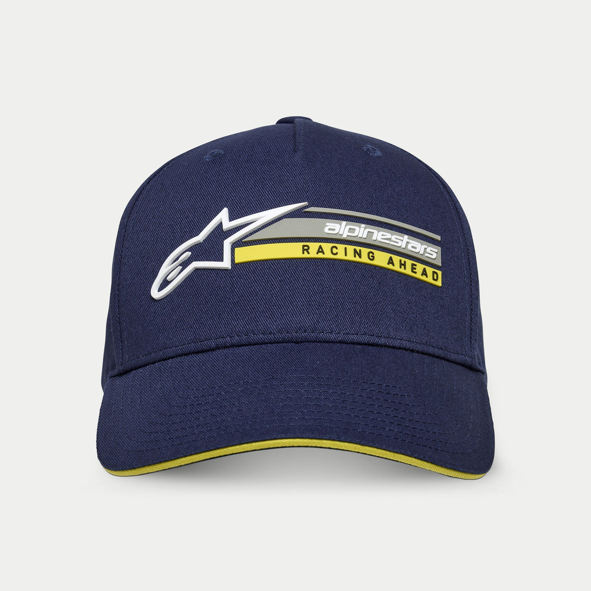 Alpinestars Par Hat, granatowa usztywniana czapka snapback z zakrzywionym daszkiem, białe logo Astars 3D i grafika „alpinestars RACING AHEAD” w kolorze szarym i żółtym, żółty akcent typu sandwich na daszku, codzienna odzież streetwearowa
