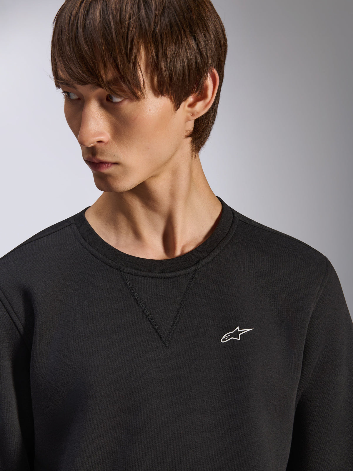 Bluza Alpinestars Positive Crew, czarny crewneck z detalem szwu V przy dekolcie, małe białe logo Alpinestars na lewej piersi, casualowa odzież uliczna inspirowana motorsportem