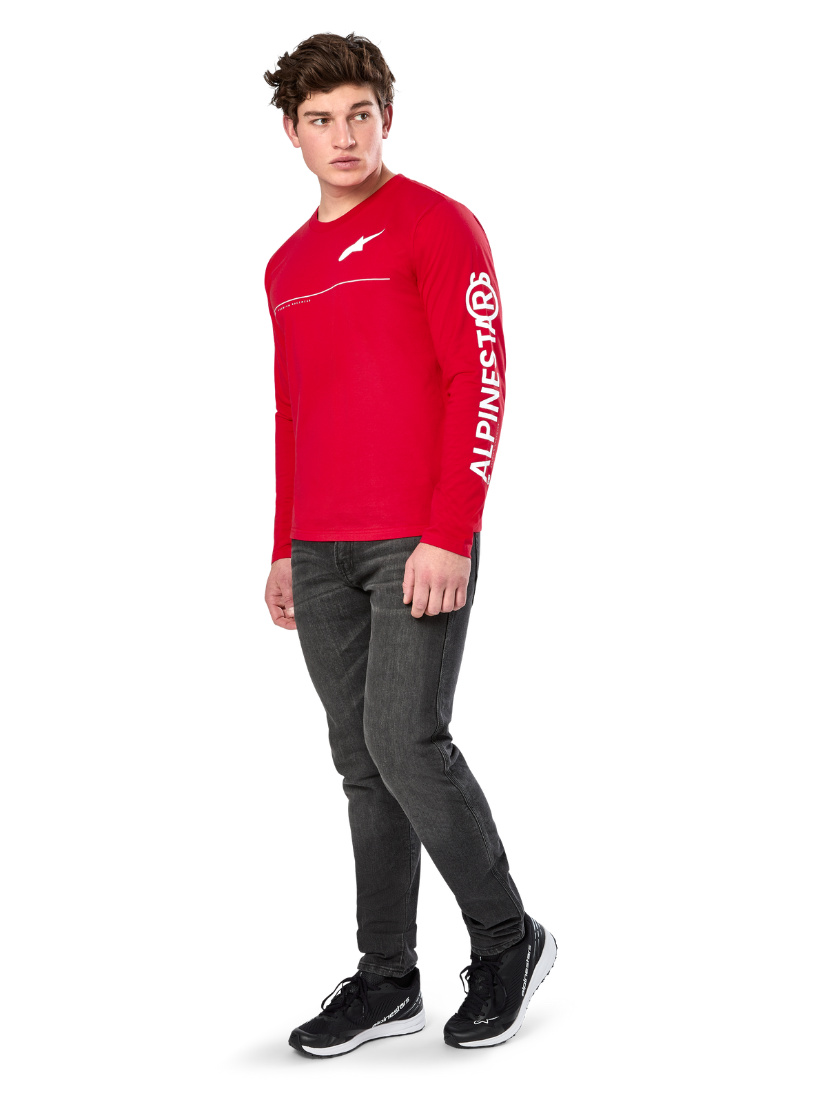 Alpinestars Committed CSF Tee, koszulka z długim rękawem, czerwona, z białym logo Astars na klatce piersiowej i brandingiem Alpinestars na rękawie, model w ciemnych dżinsach i czarnych sneakersach, casualowy motorsportowy streetwear