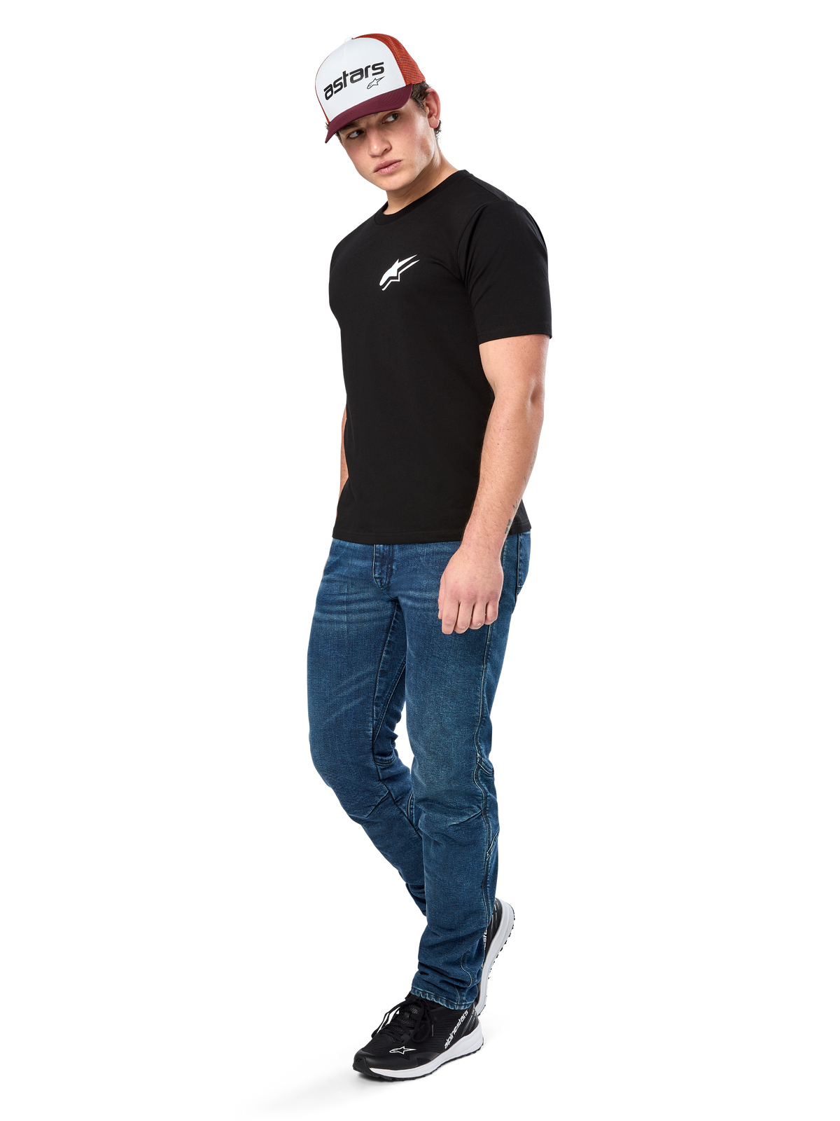 Alpinestars Formulate Csf Tee, koszulka z krótkim rękawem, czarna z białym logo Astars na klatce piersiowej, prezentowana przez modela w niebieskich jeansach, bordowo-białej czapce z daszkiem i czarnych sneakersach, codzienna odzież streetwearowa inspirowana sportami motorowymi