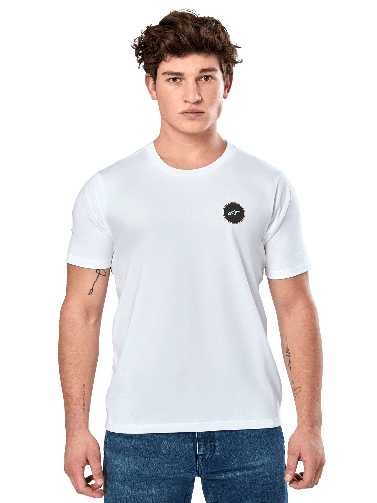 Alpinestars Dot Carbon CSF Tee, biała koszulka z krótkim rękawem, męski model w białej koszulce z małym czarnym okrągłym logo na piersi i niebieskich jeansach, casualowy styl motorsportowy