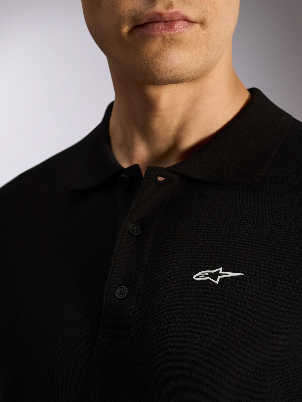 Alpinestars Endeavor Classic Polo, Black pique short sleeve polo, three-button placket, ribbed collar, white Astars logo HD print, casual motorsport-inspired streetwear