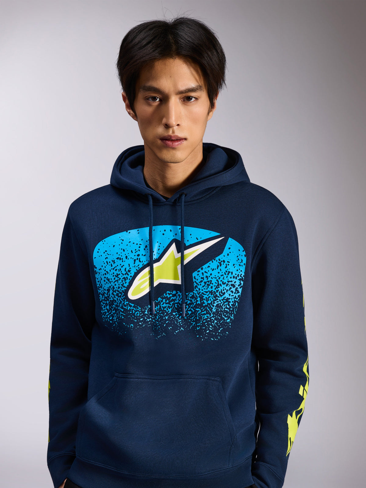 Alpinestars Obsessed Hoodie, granatowa bluza polarowa wkładana przez głowę, przednie logo Astars z niebieską gradacją MX i limonkowymi akcentami, żółte logotypy na rękawach, codzienna odzież uliczna inspirowana sportami motorowymi