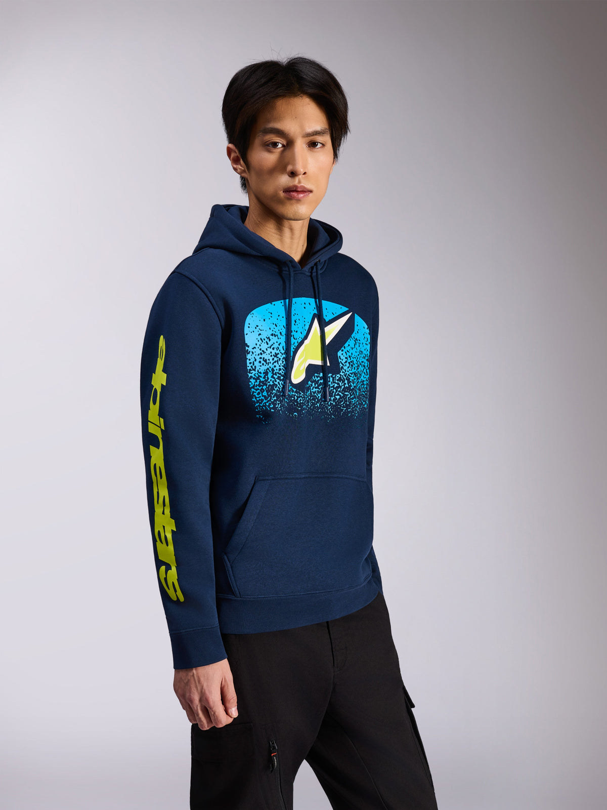 Alpinestars Obsessed Hoodie, granatowa polarowa bluza z kapturem, z logo Astars z przodu z jasnoniebieską gradacją MX i żółtym napisem na rękawie, kaptur ze sznurkiem, codzienna odzież motorsport