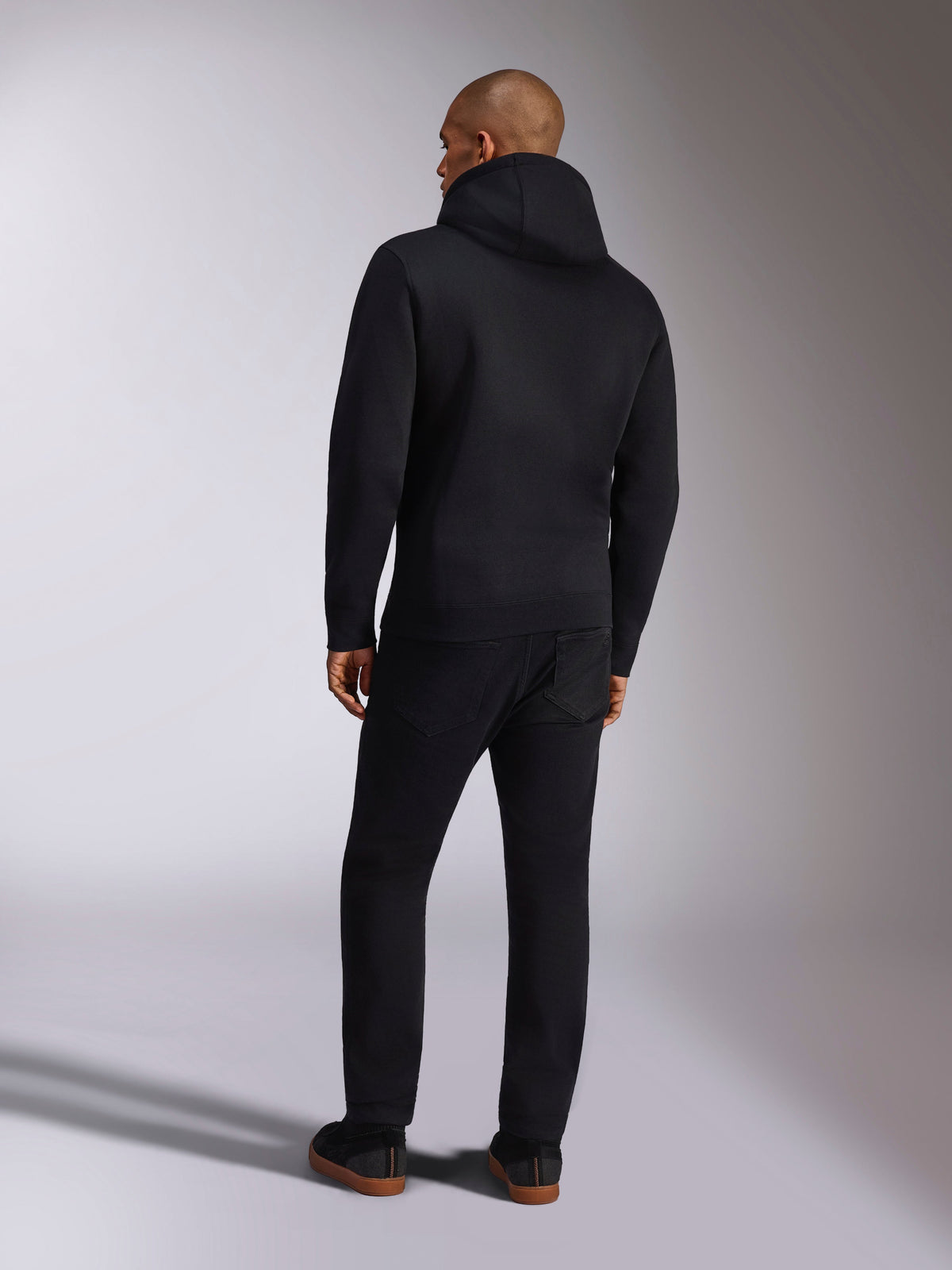 Alpinestars Ellipsoid Hoodie, codzienna odzież sportowa, czarna polarowa bluza z kapturem, widok z tyłu, długie rękawy i żebrowany ściągacz, zestawiona z czarnymi spodniami, nowoczesny design inspirowany sportami motorowymi