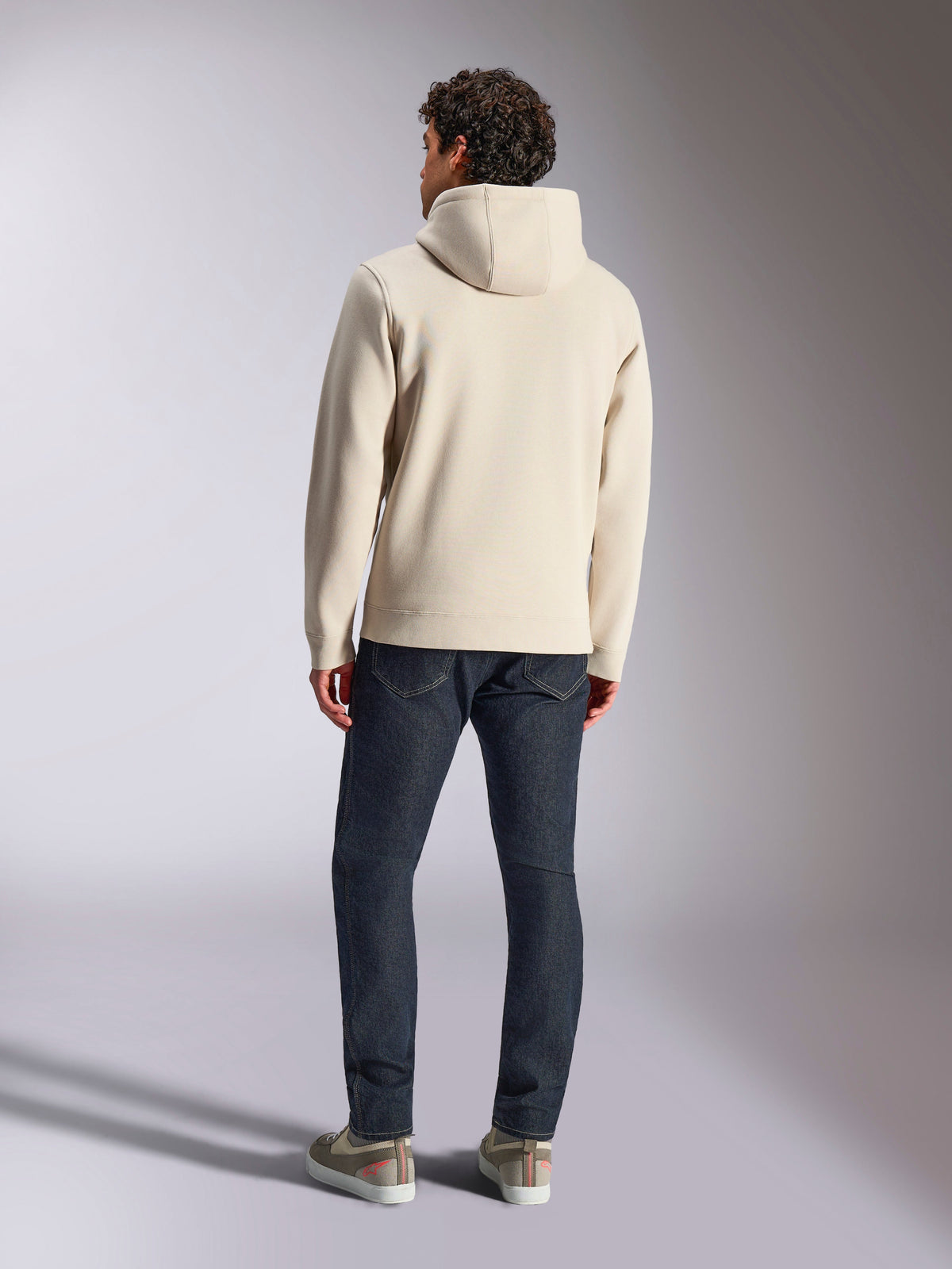 Alpinestars Pulse Hoodie, kolor złamanej bieli, widok od tyłu mężczyzny ubranego w codzienną bluzę z kapturem z polaru, ciemne jeansy i sneakersy, nowoczesny sportowy design