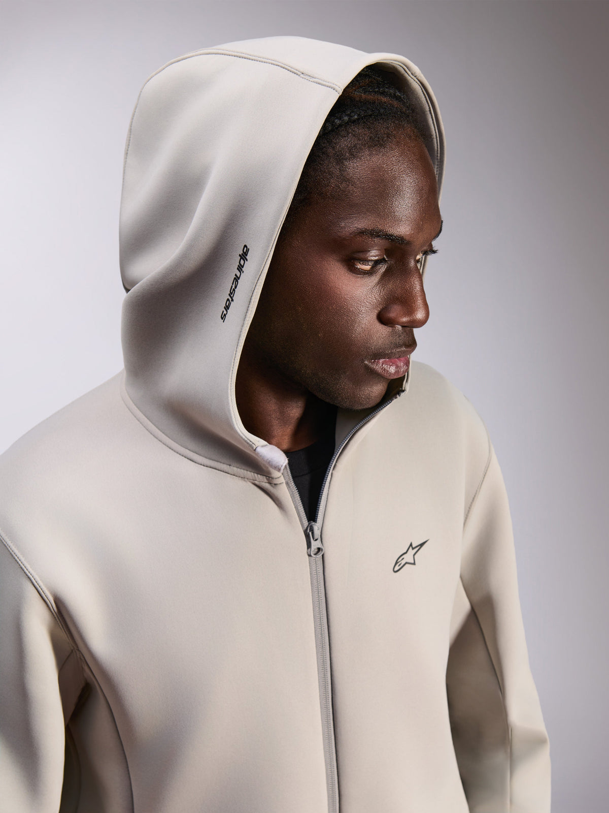 Alpinestars Cypher Hoodie, Zip-up Fleece Hoodie, Cement Gray, worn with hood up, featuring Alpinestars word logo on hood and small Astars chest logo, casual motorsport-inspired streetwear