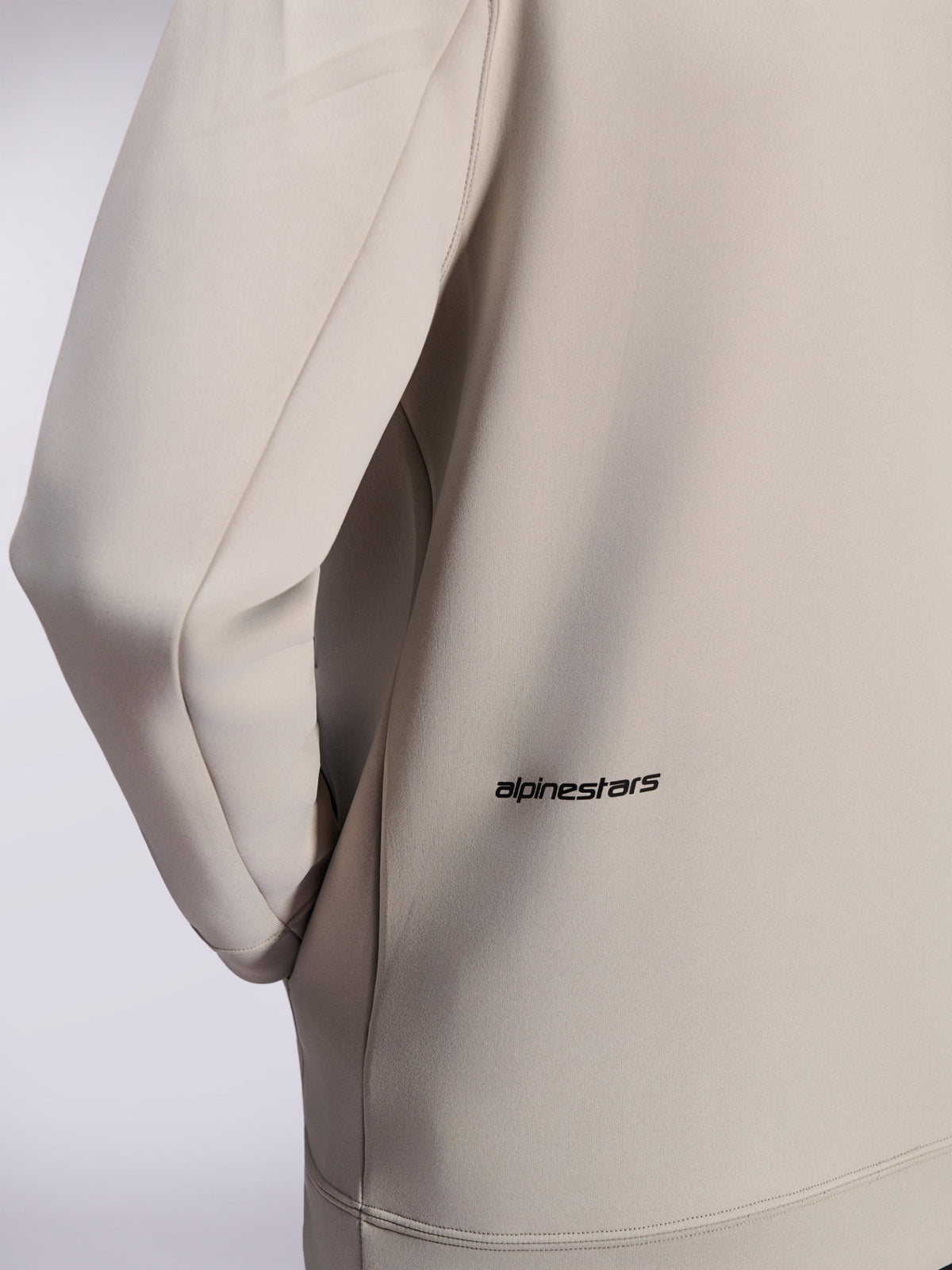 Alpinestars Cypher Hoodie, double face fleece zip hoodie, Cement Gray, close-up of small black Alpinestars word logo on the lower back, detail of on-seam pocket and smooth fabric texture