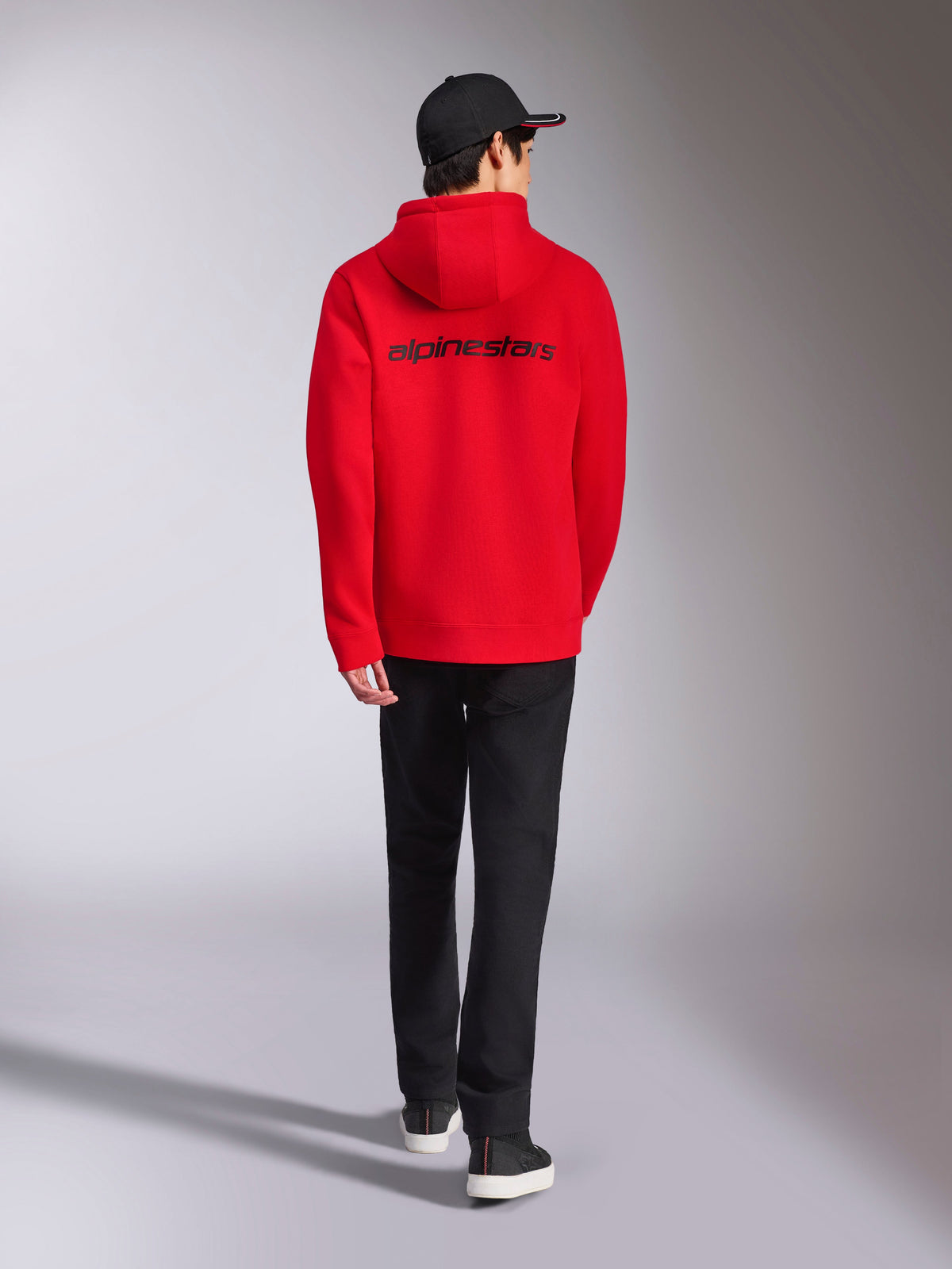 Alpinestars Transverse Hoodie, czerwona bluza z kapturem w stylu streetwear, widok z tyłu z czarnym logotypem Alpinestars, polarowa bluza, zestawiona z czarną czapką i czarnymi spodniami
