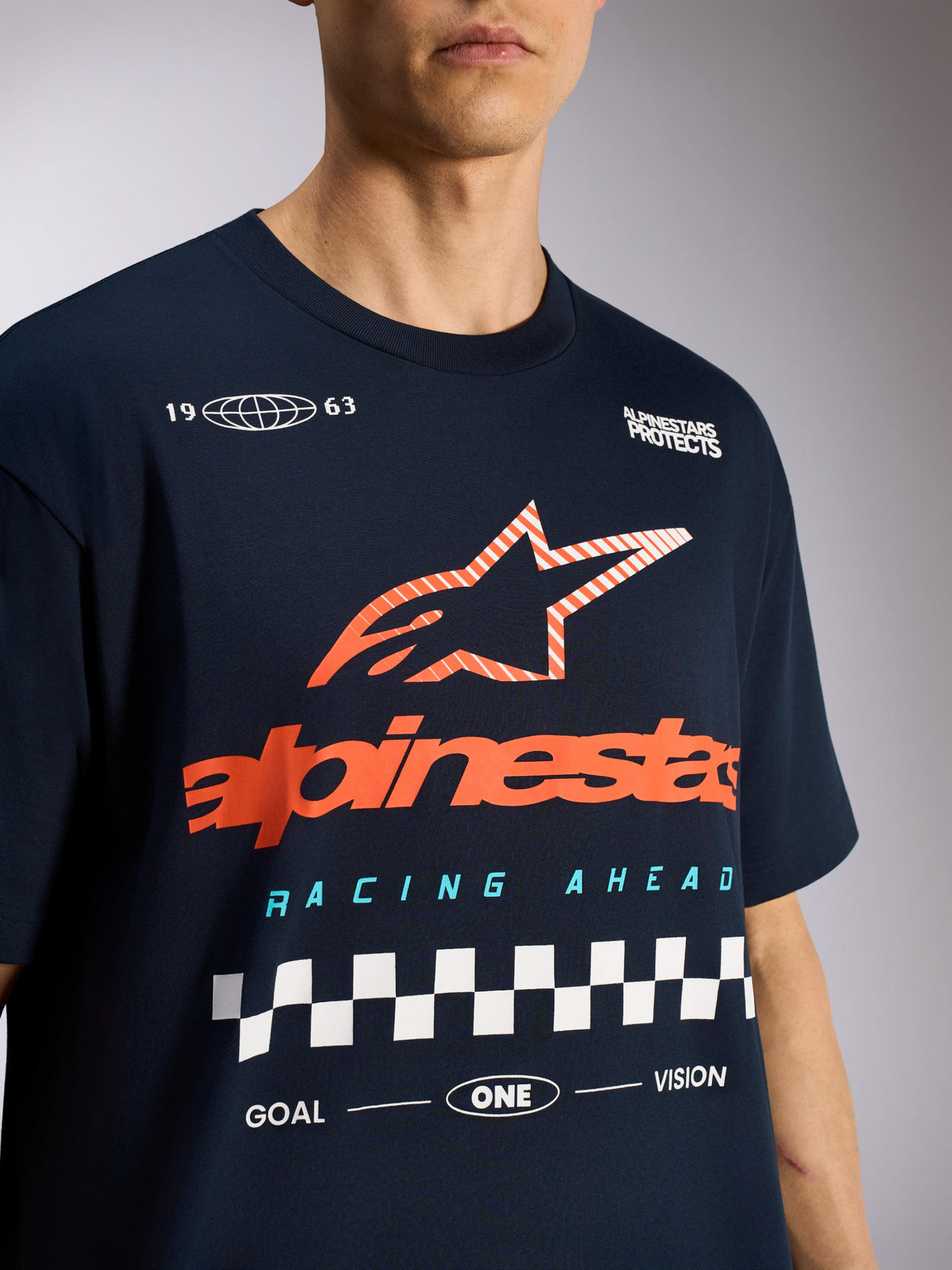 Alpinestars Aplomb Oversized CSF Tee, koszulka z krótkim rękawem, granatowa, z dużym pomarańczowym pasiastym logo gwiazdy Astars i wyścigową grafiką w szachownicę, codzienna odzież sportowa typu motorsport