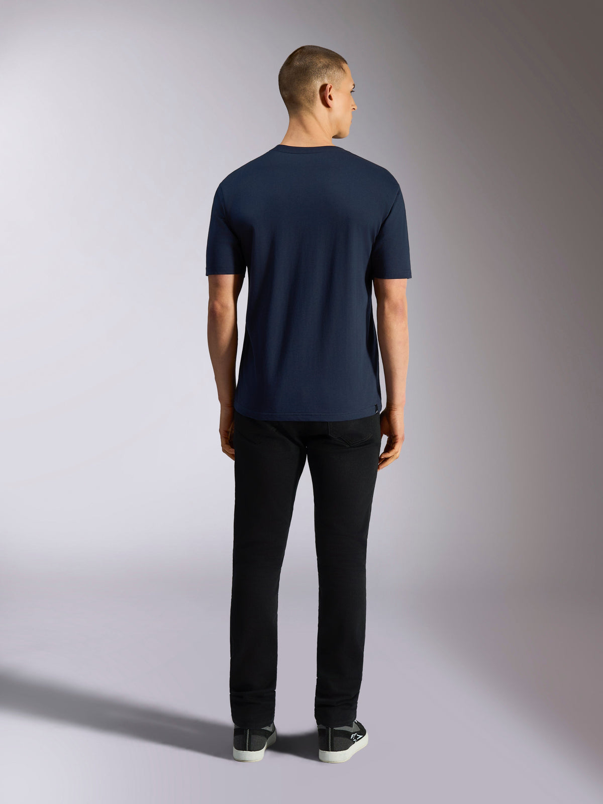 Alpinestars Noka CSF Tee, koszulka z krótkim rękawem, granatowa, widok z tyłu na mężczyznę ubranego w koszulkę, czarne spodnie i sneakersy, casualowa odzież uliczna w stylu motorsport