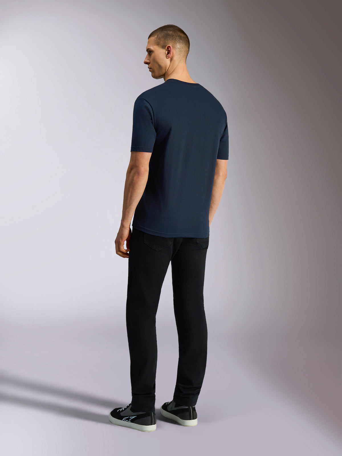 Alpinestars Noka CSF Tee, koszulka z krótkim rękawem, granatowa, widok z tyłu na modelu ubranym w czarne spodnie i sneakersy, casual motorsport streetwear