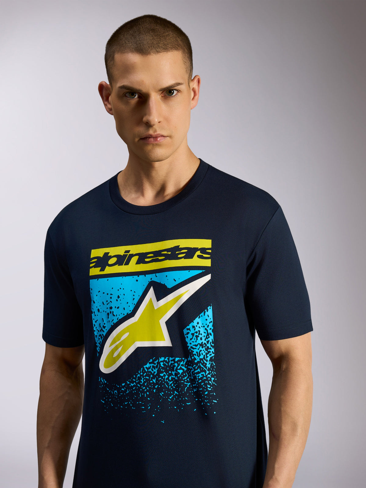 Alpinestars Noka CSF Tee, granatowa koszulka z krótkim rękawem, z przodu logo Astars z żółtym napisem i niebieską nakrapianą grafiką, codzienna odzież sportowa typu motorsport