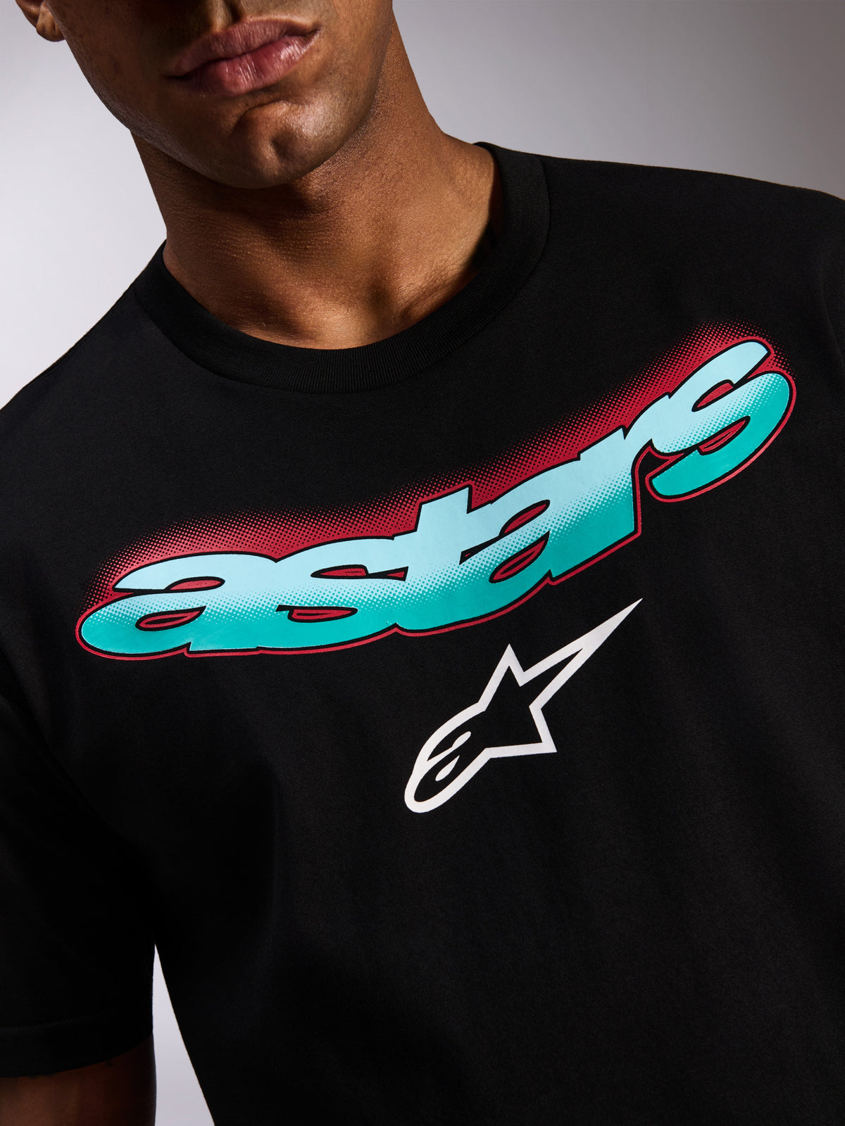 Alpinestars Ellipsoid CSF Tee, czarna koszulka z krótkim rękawem, zbliżenie na grafikę z przodu z morsko-niebieskim gradientem napisu Astars, czerwonym cieniem w technice halftone i białym logo gwiazdy, codzienna odzież streetwear w stylu motorsport