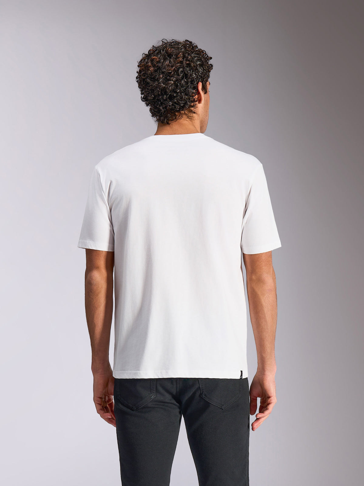 Alpinestars Plate CSF Tee, koszulka z krótkim rękawem, biała, widok z tyłu, noszona z czarnymi spodniami, casualowy motorsportowy streetwear