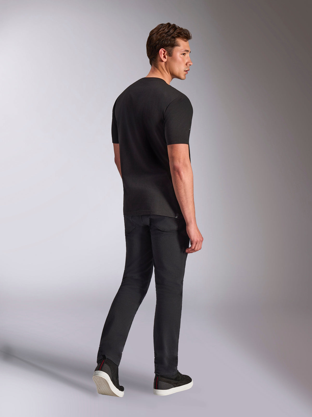 Alpinestars Trifecta CSF Tee, koszulka z krótkim rękawem, czarna, widok z tyłu na mężczyznę ubranego w koszulkę, czarne dżinsy i tenisówki, codzienna odzież uliczna w stylu motorsport