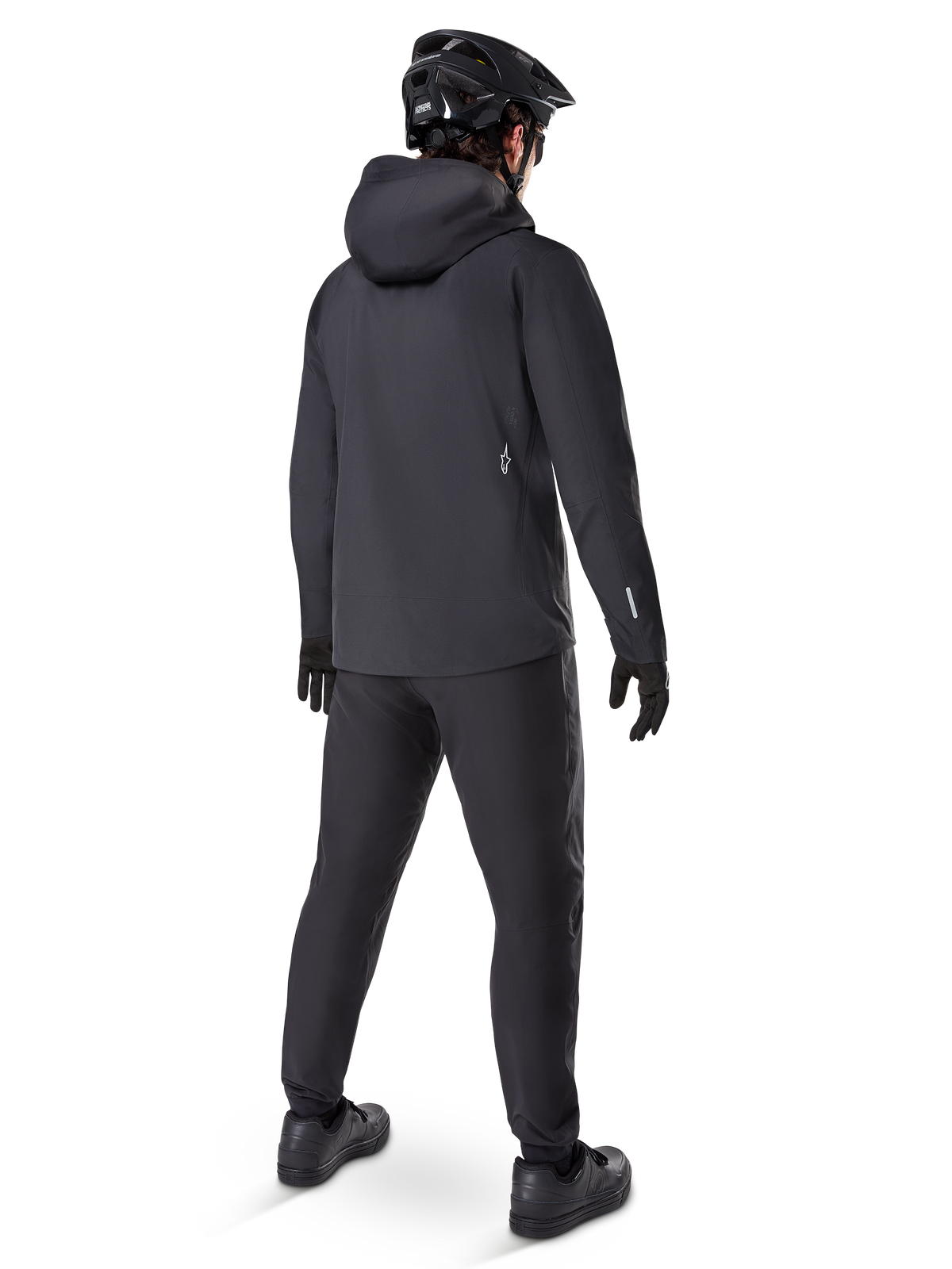 Alpinestars A-Dura Elite Waterproof Jacket, czarna, widok z tyłu prezentujący kaptur na kask i dłuższy tylny rąbek, w zestawieniu z pasującymi czarnymi spodniami MTB, rękawicami i kaskiem dla pełnej ochrony na szlaku w każdych warunkach pogodowych.