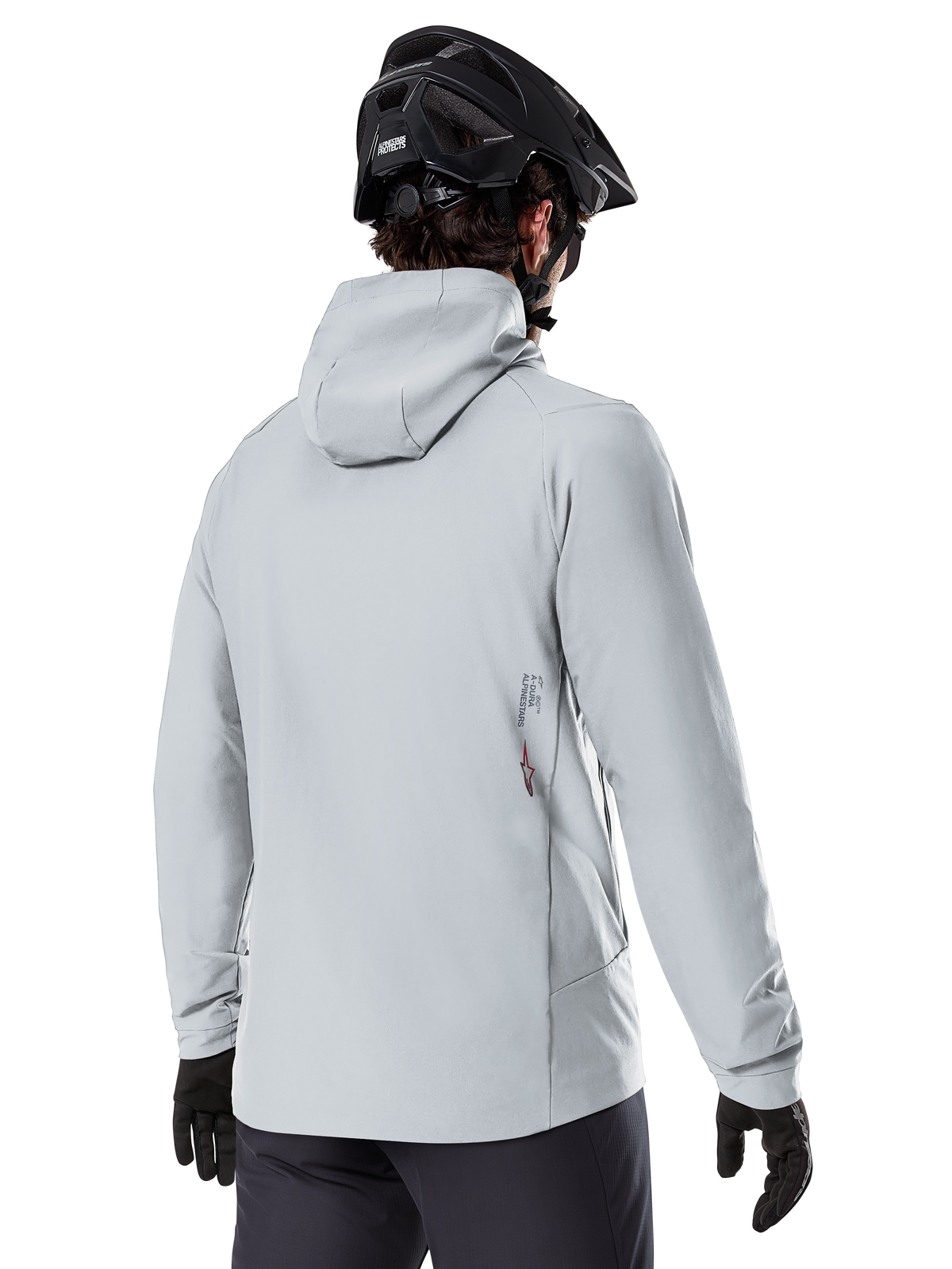 Kurtka Alpinestars A-Dura Thermal, Titanium Gray, widok od tyłu rowerzysty w ocieplanej kurtce z kapturem, w zestawieniu z czarnym kaskiem MTB i czarnymi rękawiczkami, małe logo Alpinestars na dole pleców, zaprojektowana do jazdy MTB w niskich temperaturach
