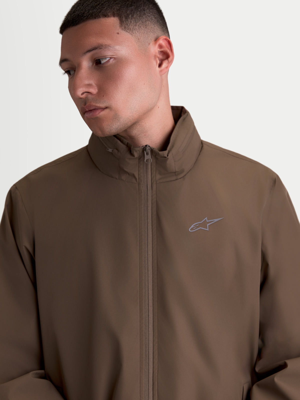 Alpinestars Overhaul Racer, męska lekka kurtka sportowa, brązowa, wysoki kołnierz z ukrytym kapturem i małe logo HD na piersi, styl inspirowany motorsportem