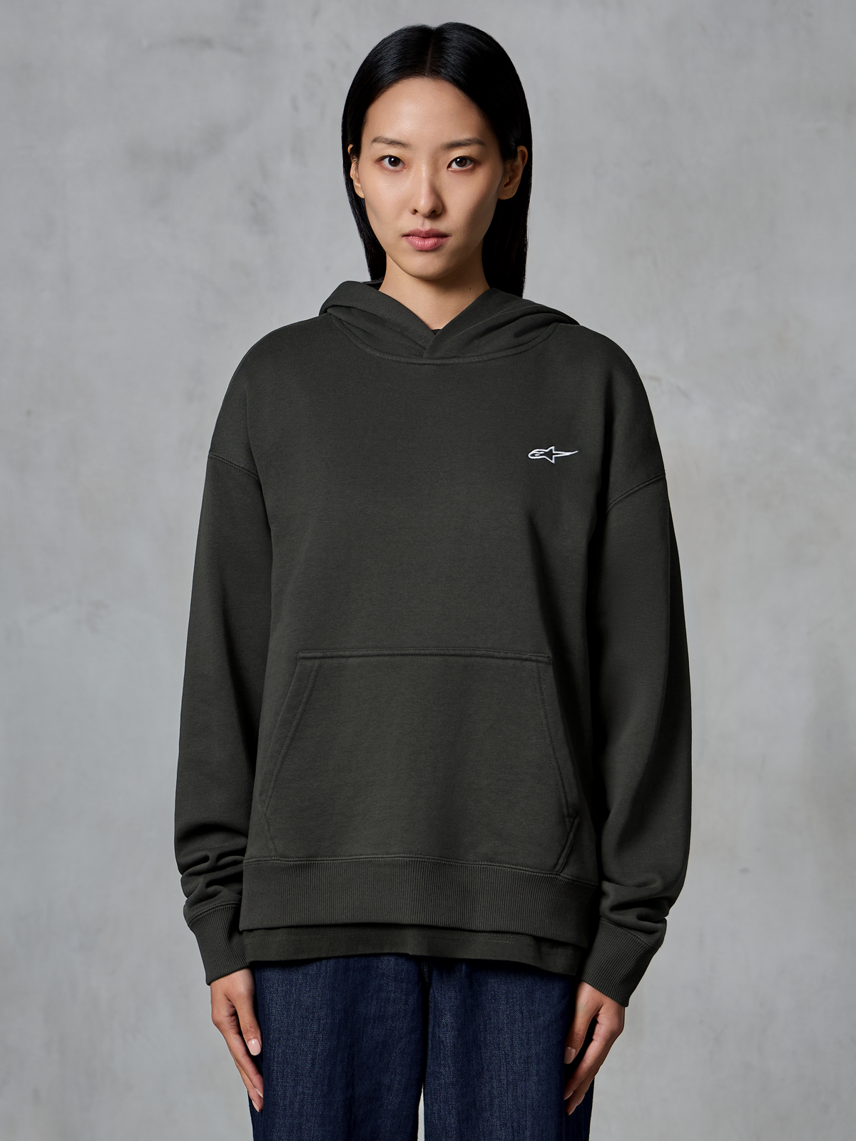 Alpinestars Essentials Ageless Hoodie, Off Black, worn by a model, featuring a small white Astars logo on the chest, front kangaroo pocket, stone-wash finish, casual premium fleece streetwear