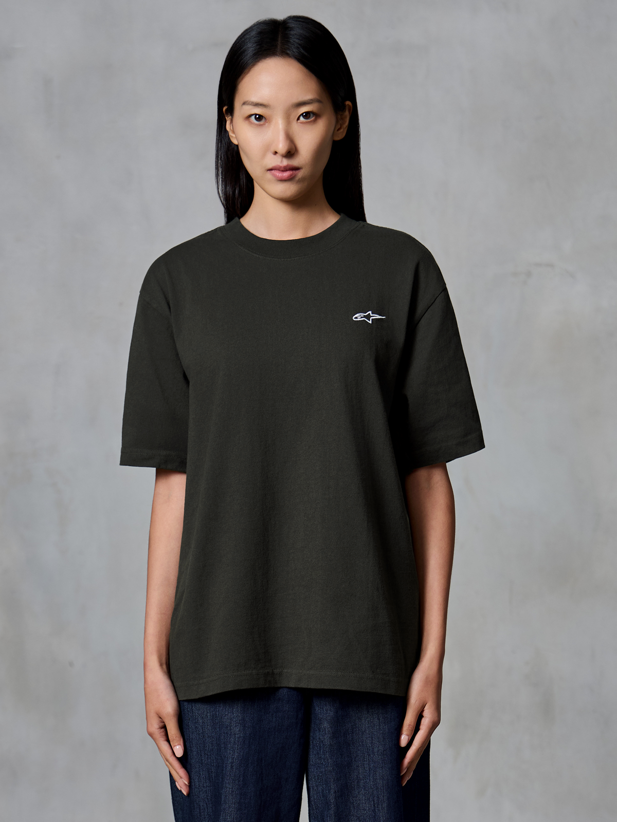 Alpinestars Essentials Ageless SS Tee, koszulka z krótkim rękawem, kolor Off Black, prezentowana na modelce, luźny krój z małym białym logo Alpinestars na lewej piersi, casualowa odzież lifestyle