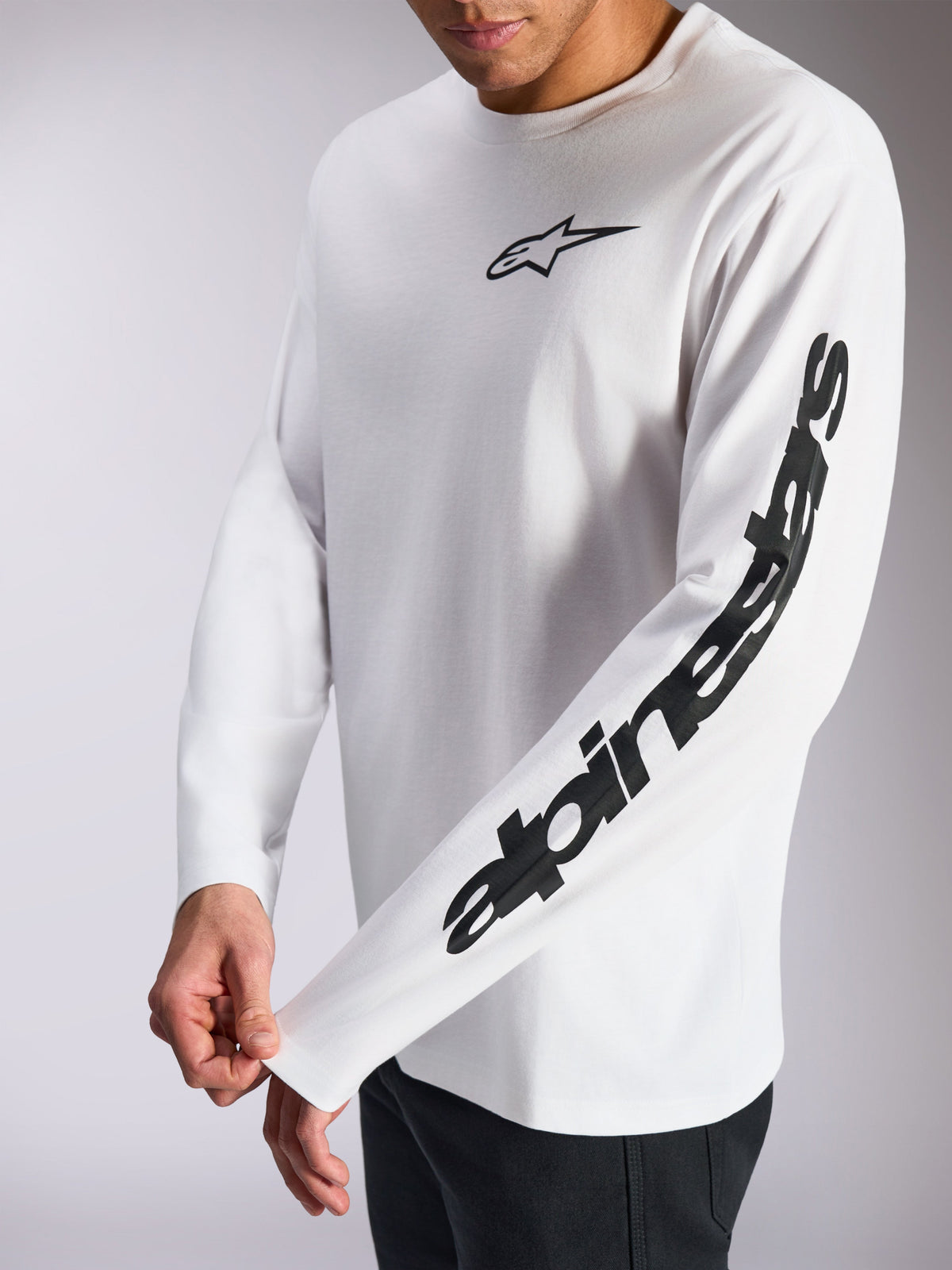 Alpinestars Trackside CSF Tee, koszulka z długim rękawem, biało-czarna, małe czarne logo z gwiazdą na piersi i wyraźny logotyp na rękawie, codzienna odzież streetwear inspirowana sportami motorowymi