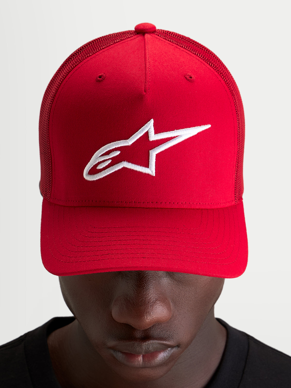Alpinestars Ageless Snapback Hat, czerwona czapka z daszkiem ze sportowym, usztywnionym panelem, haftowanym białym logo Astars i zakrzywionym daszkiem, prezentowana na modelu