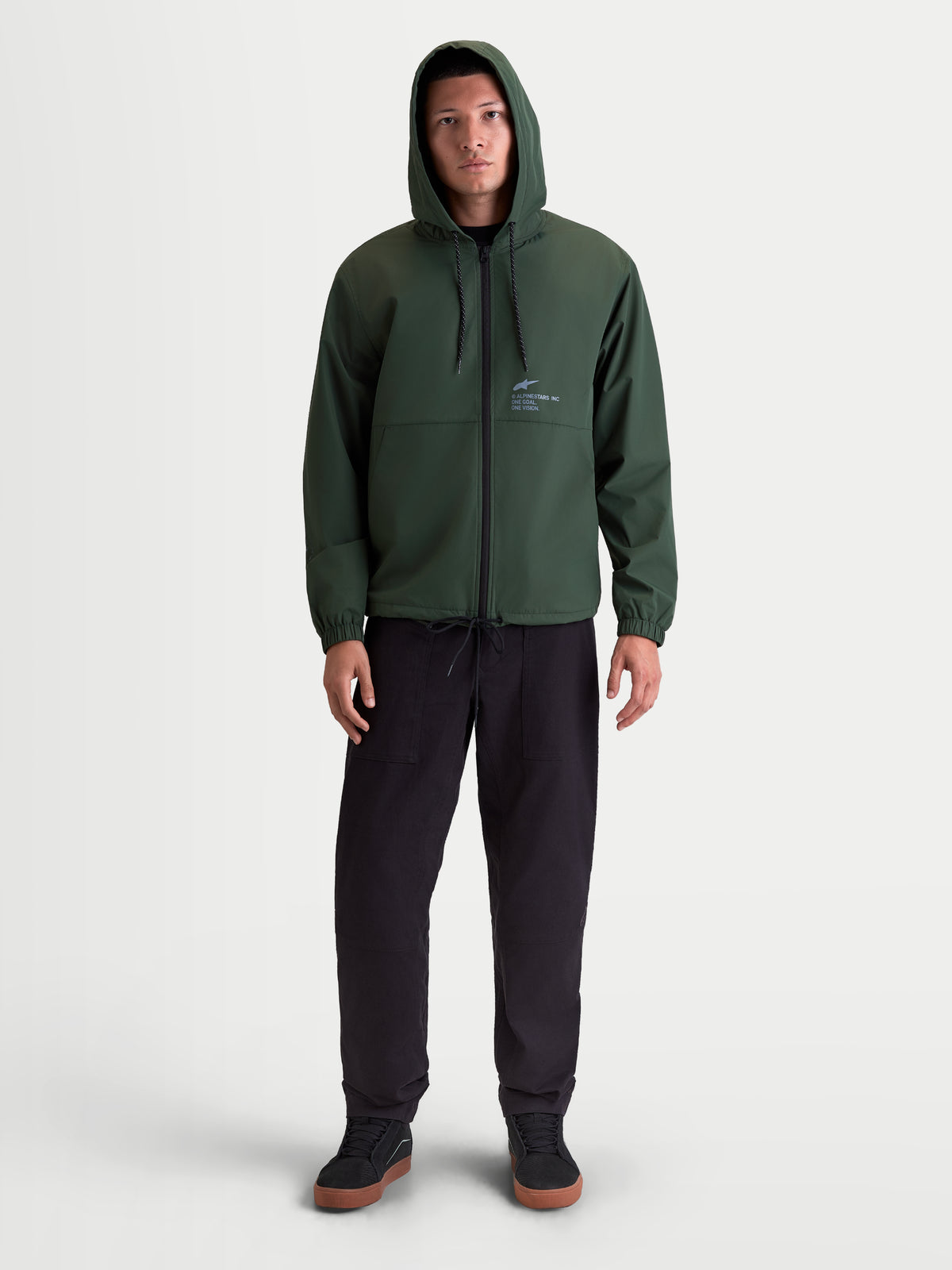 Alpinestars Kurtka Speeder Resolve Ochrona Przed Wiatrem, zielona męska kurtka z kapturem, lekka wiatrówka sportswear, regulowany kaptur, zamek z odwrotną spiralą, logo Alpinestars na piersi, widok na modelu z przodu.