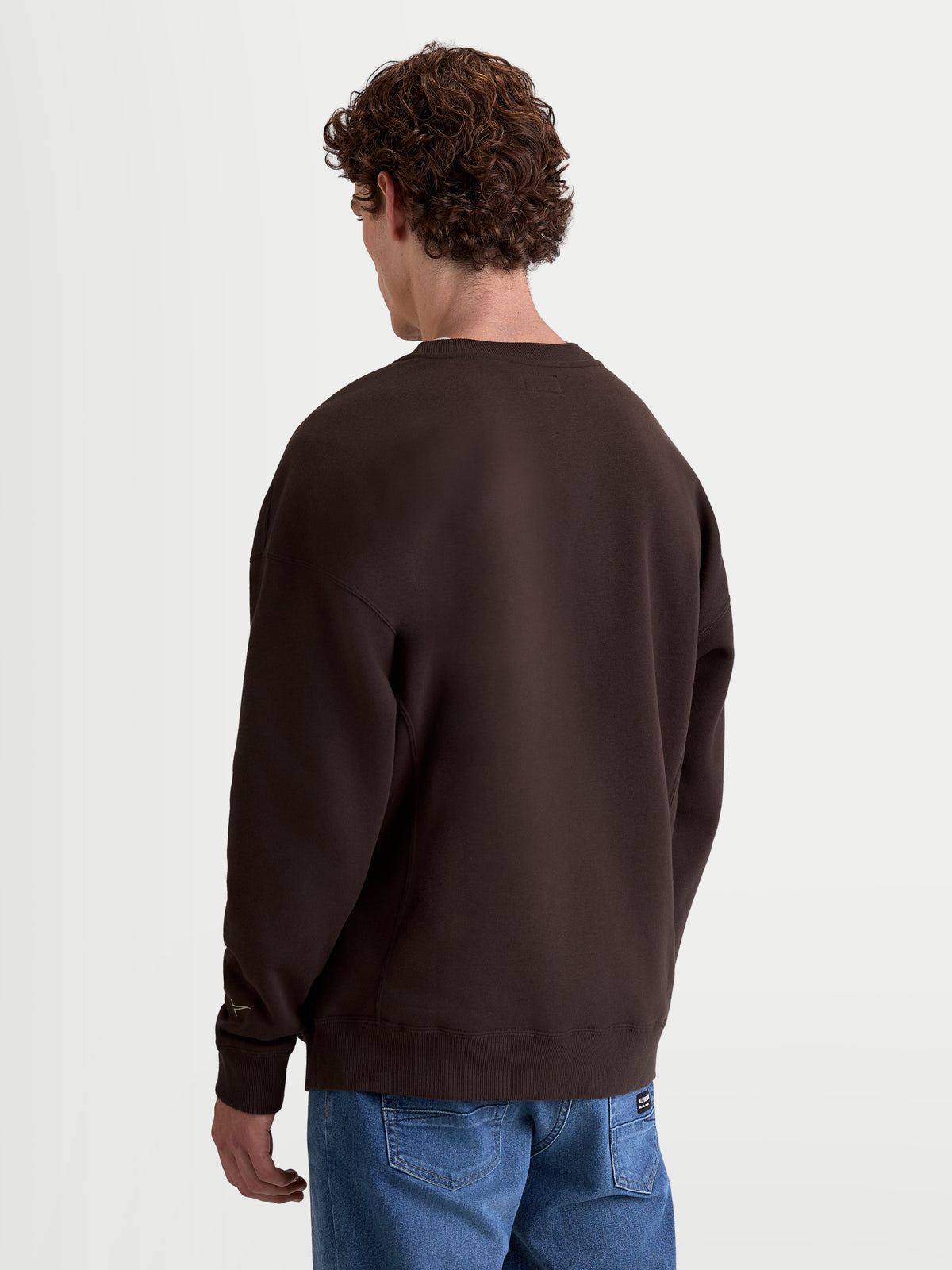 Alpinestars Guise Oversized Crew, brązowy pulower z polaru typu crewneck, krój oversized, widok z tyłu na modelu, wykonany z mieszanki bawełny premium i poliestru z recyklingu, lifestyle'owa odzież sportowa.