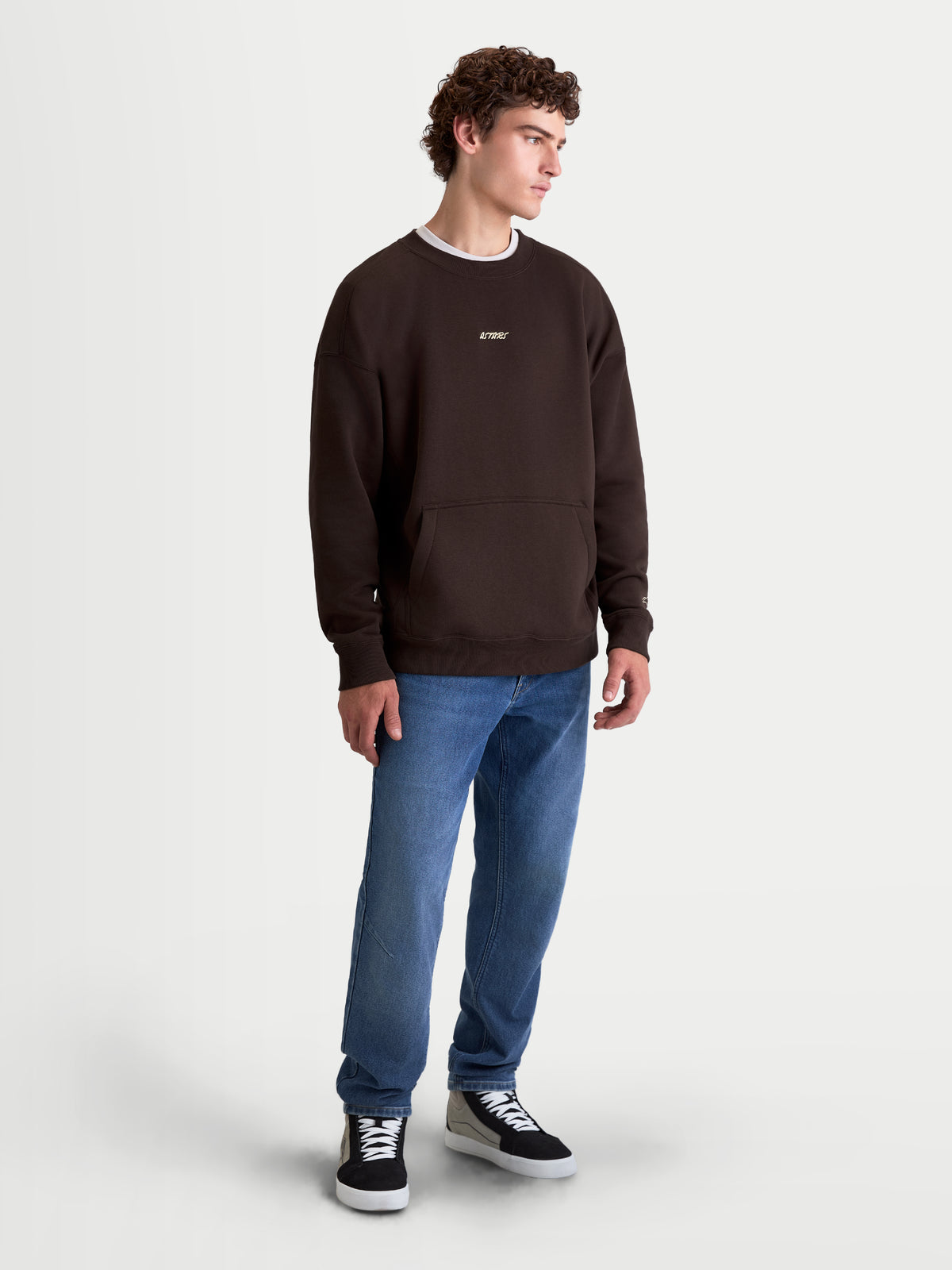 Alpinestars Guise Oversized Crew, brązowa męska bluza o luźnym kroju, haftowane logo Astars na piersi, kieszeń kangurka i prążkowane mankiety, odzież sportowa inspirowana motorsportem, widok na modelu.