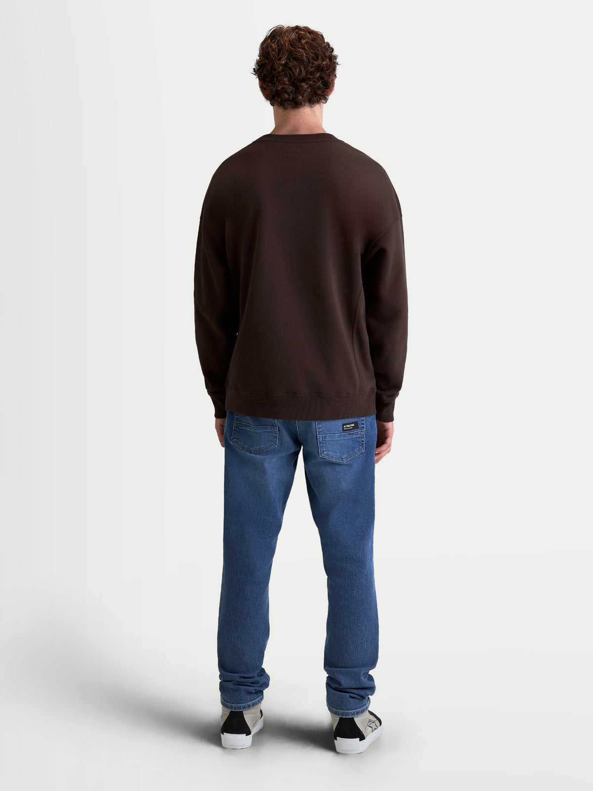 Alpinestars Guise Oversized Crew, brązowa bluza z polaru typu pullover, widok z tyłu na modelu, luźny krój oversized, ściągacze przy mankietach i na dole, mieszanka bawełny i poliestru z recyklingu, casualowa odzież sportowa.