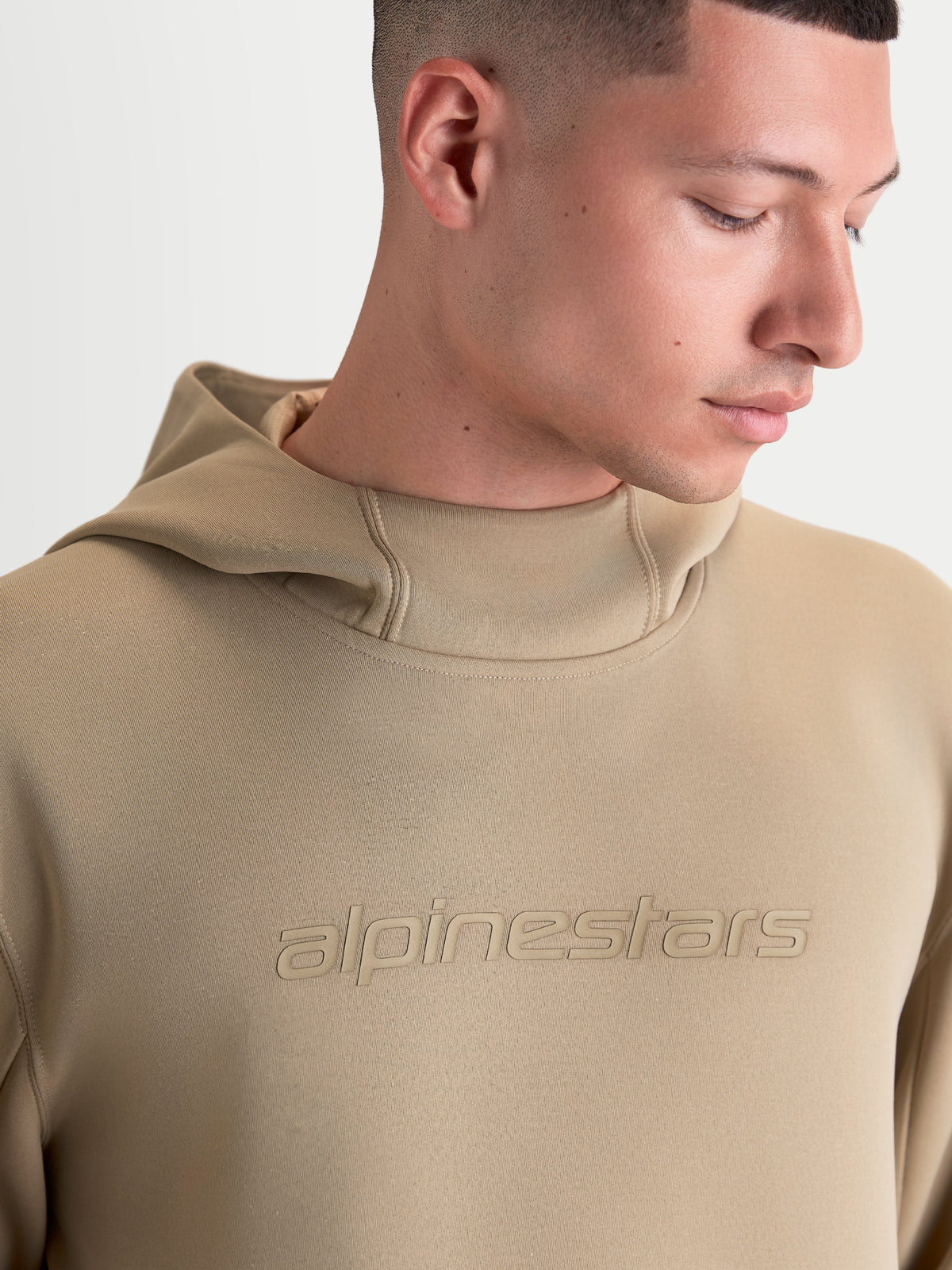 Alpinestars Bluza z kapturem Datrix, brązowa sportowa bluza dla mężczyzn i kobiet, tonalne logo Alpinestars, kaptur z siatkową podszewką, zbliżenie na modela pokazujące konstrukcję z polaru premium.