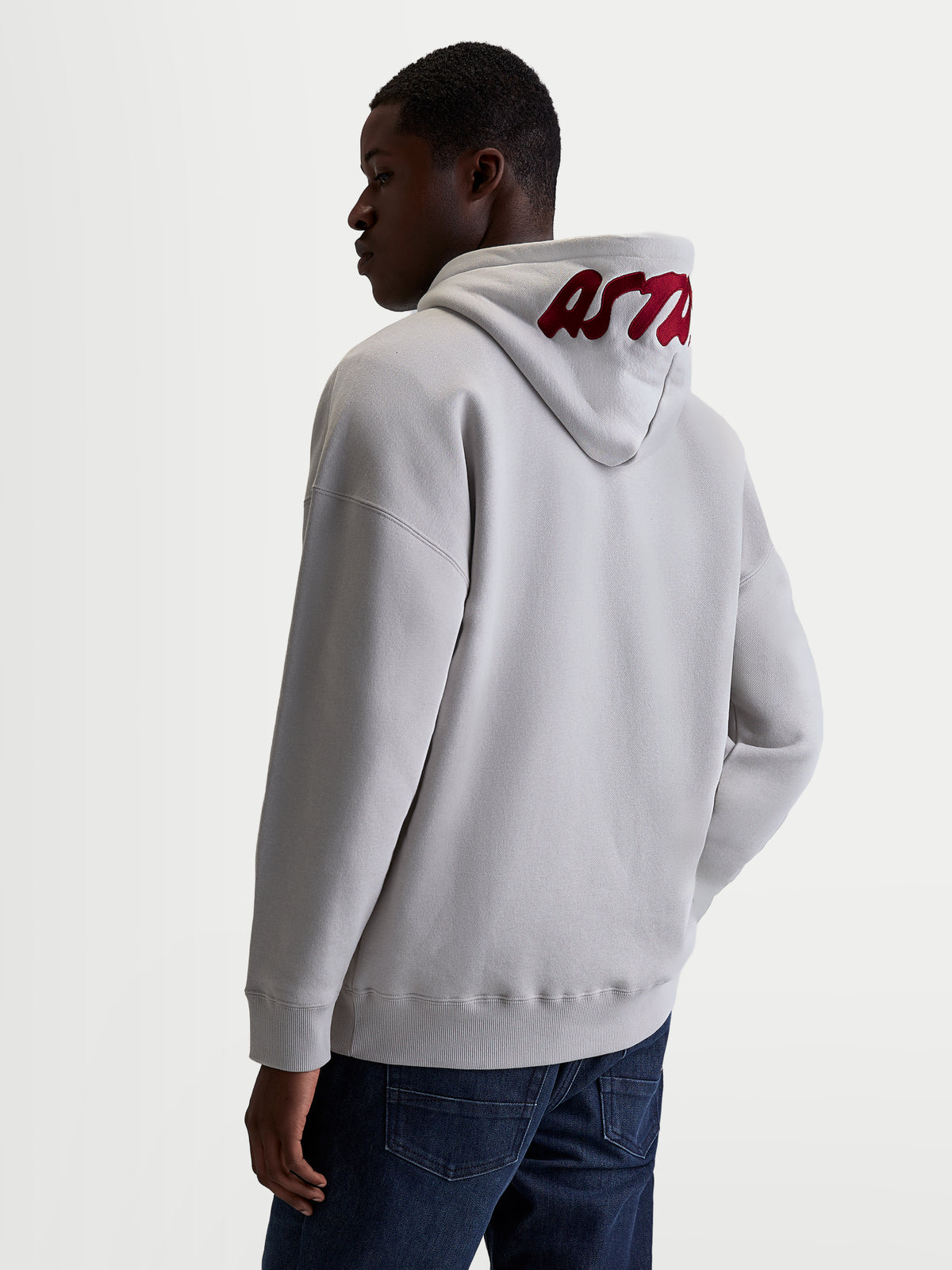 Alpinestars Pioneer Oversized Hoodie, Sportswear Zip Fleece, Unisex, Cement Gray and Red, features a relaxed oversized fit and premium red embroidered logo on the hood. Made from a soft cotton and recycled polyester blend for casual everyday comfort. Back view on model.