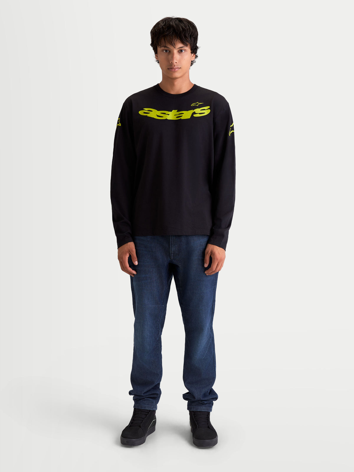 Alpinestars Koszulka Velocifier CSF, czarna koszulka z długim rękawem typu unisex, żółta zakrzywiona grafika Astars na piersi, logo na ramionach i prążkowane mankiety, casualowa odzież sportowa inspirowana motorsportem, model prezentujący produkt