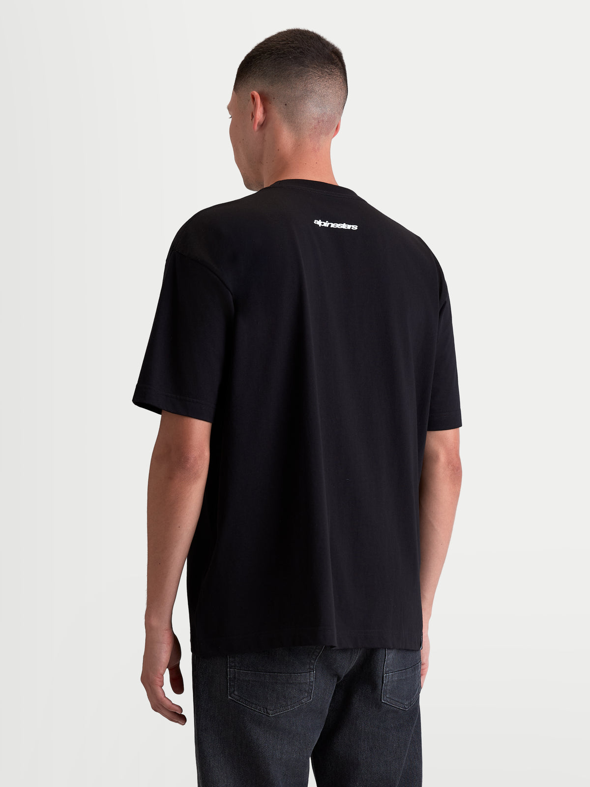 Alpinestars Prelude Oversized CSF, męska koszulka z krótkim rękawem, czarna z białym napisem Alpinestars na plecach, luźny krój sportswear, wykonana z mieszanki bawełny i poliestru, widok z tyłu na modelu.