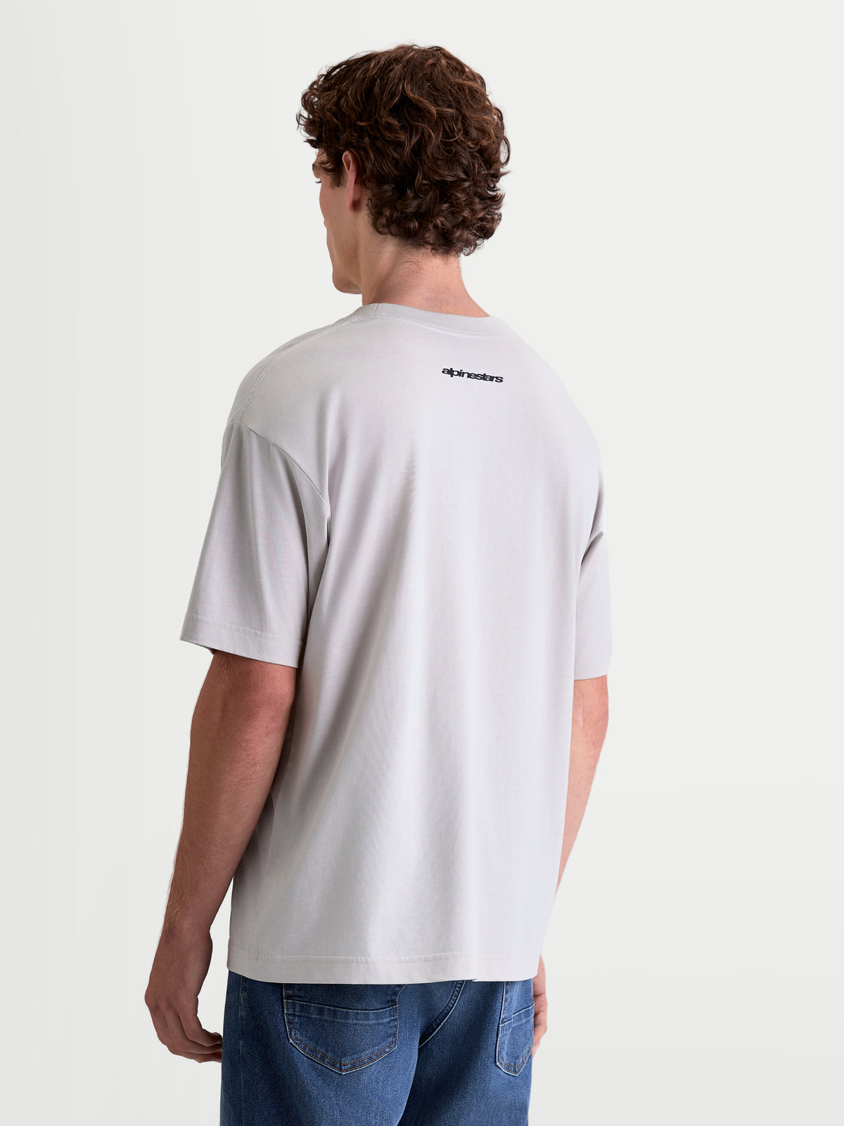 Alpinestars Prelude Oversized CSF, szara koszulka z krótkim rękawem, krój oversize, małe czarne logo Alpinestars na plecach, widok na modelu z tyłu, casualowa odzież sportowa.