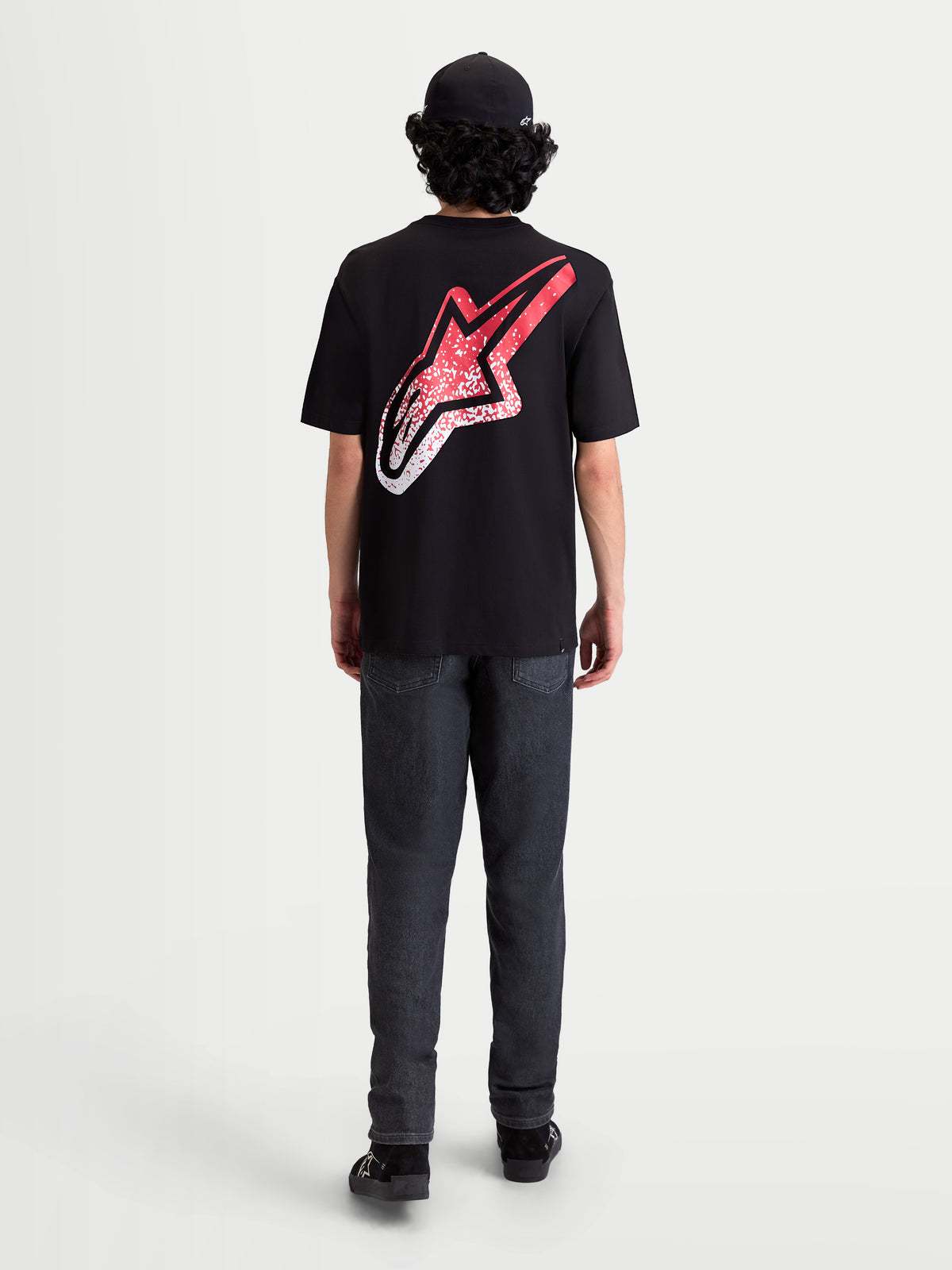 Alpinestars Meteor CSF Tee, czarna koszulka z krótkim rękawem, widok z tyłu na modelu, duże logo Astars na plecach z czerwono-białym gradientem w stylu MX, casualowa odzież sportowa.