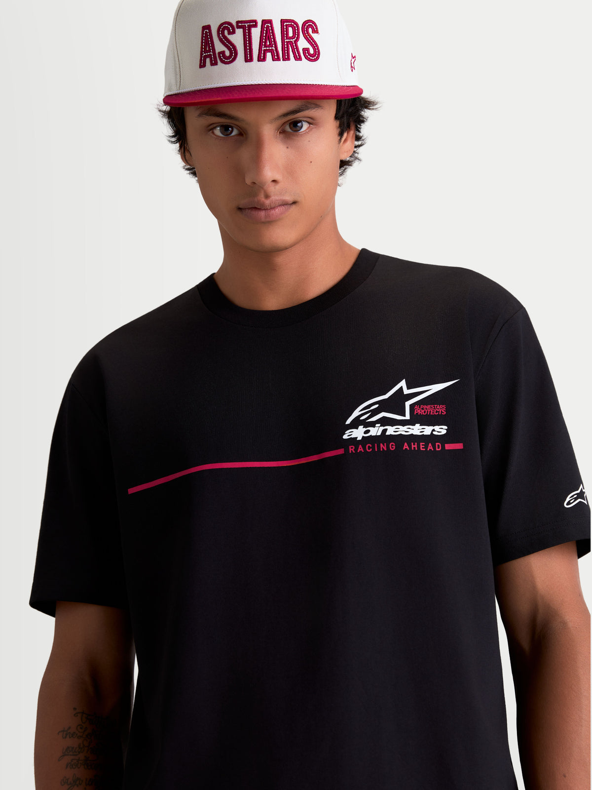 Alpinestars P1 CSF, czarna koszulka z krótkim rękawem, białe logo i czerwony pasek wyścigowy, t-shirt sportswear unisex z mieszanki bawełny i poliestru, model na zdjęciu