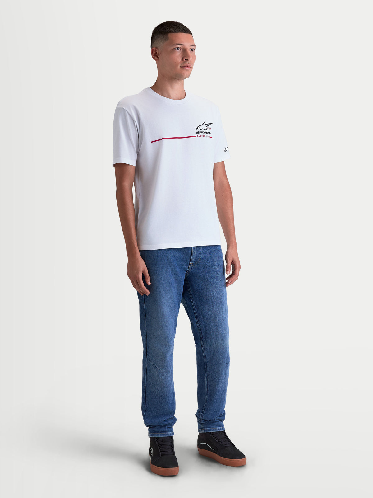 Alpinestars Koszulka P1 CSF, biała koszulka z krótkim rękawem na modelu, czarna grafika logo Astars z czerwonym paskiem wyścigowym na piersi, casualowa odzież sportowa w stylu motorsport